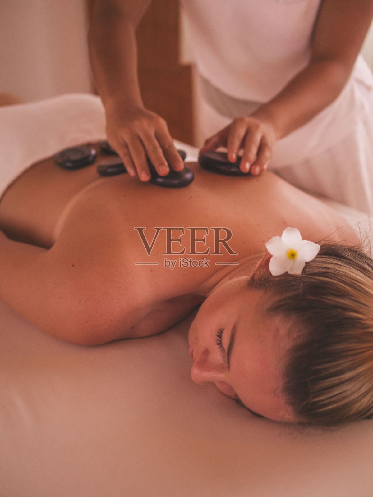 垂直拍摄的一个白人妇女正在温泉接受热石按摩照片摄影图片