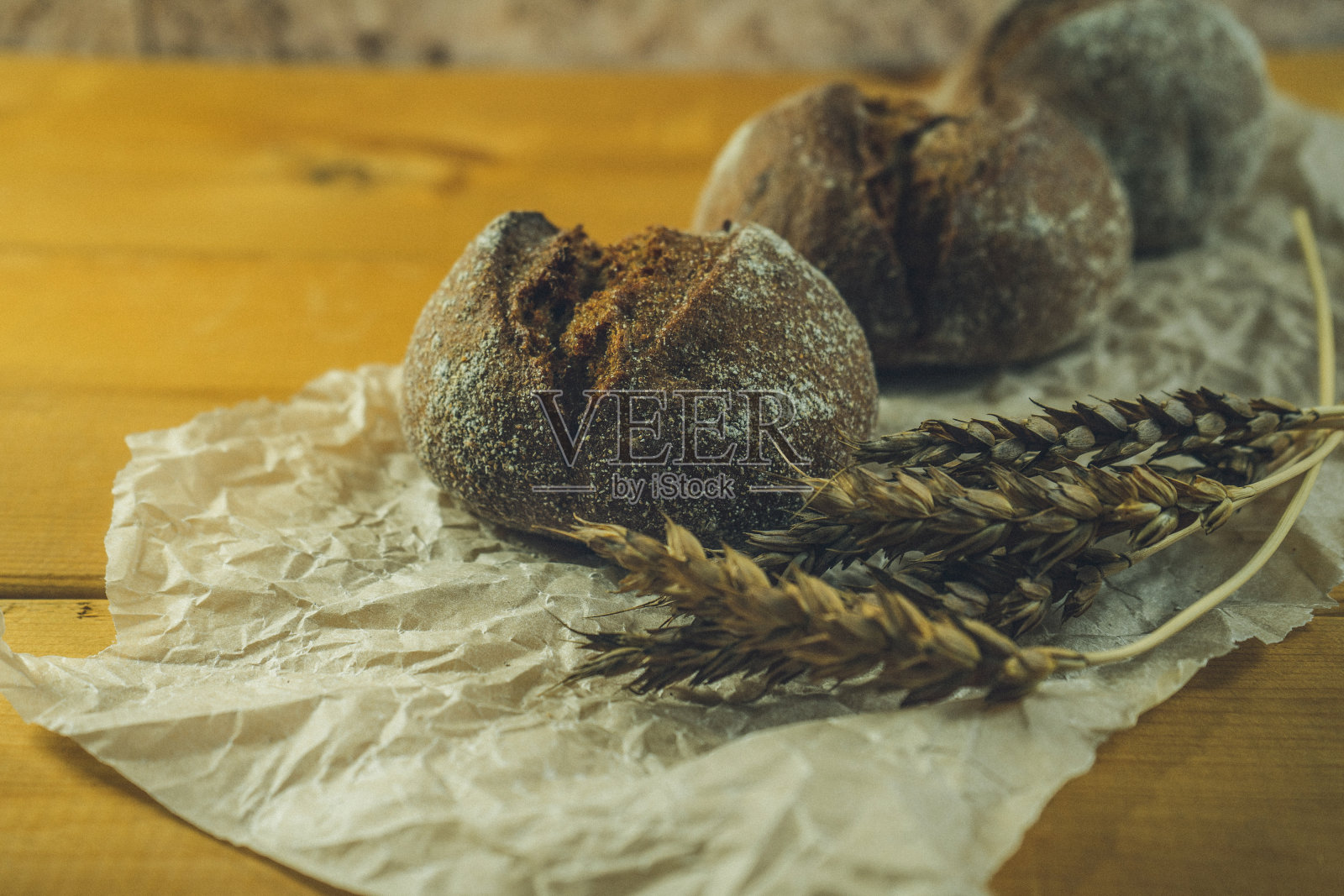 自制全麦酸面包，麦粒和小穗。小麦面包的小穗。新鲜小麦面包的小穗放在棕色的木质背景上。照片摄影图片