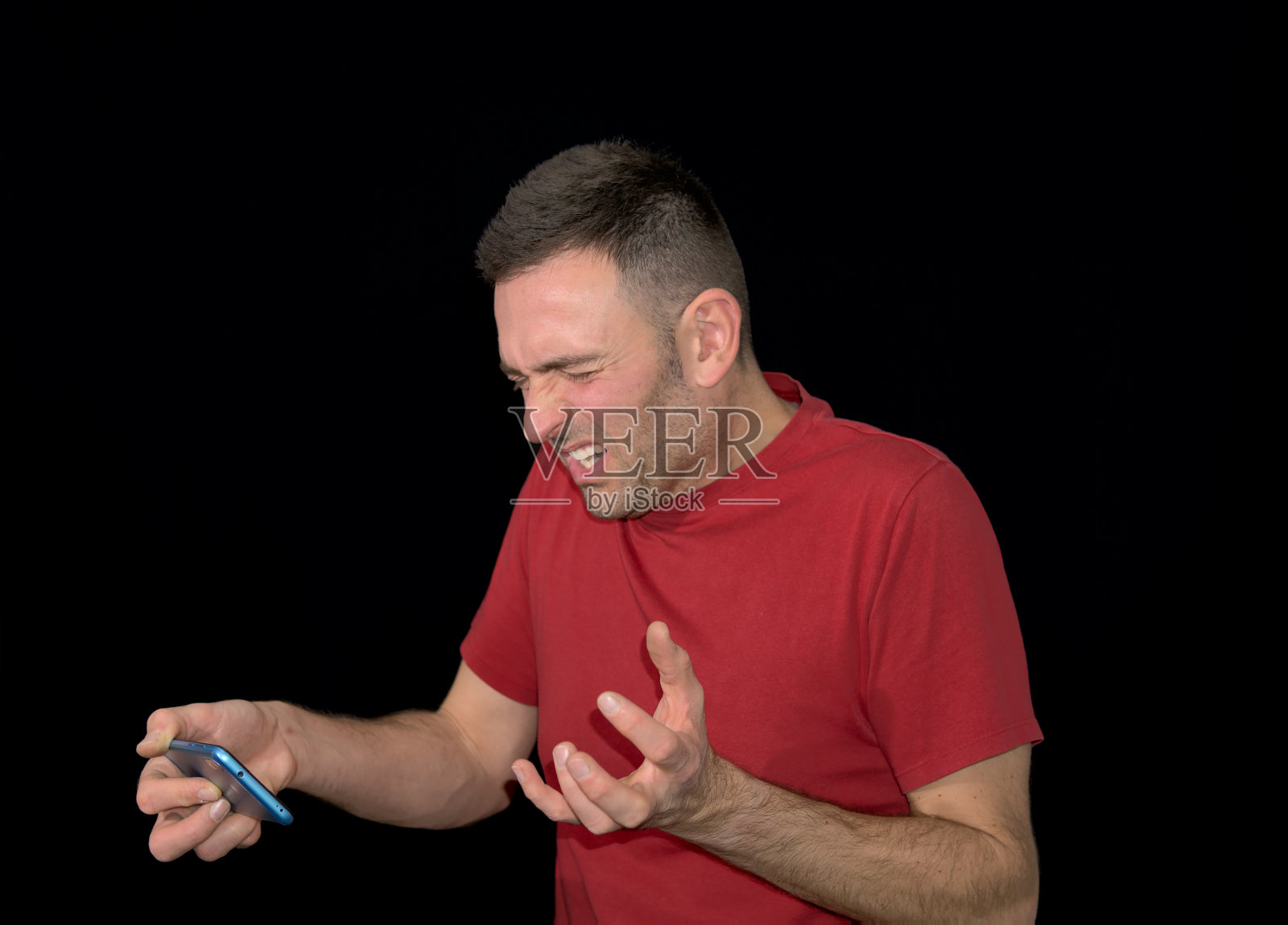 身穿红色t恤的国家队球迷在看世界杯足球赛时用手机哭进球失望。2022年在卡塔尔举办。照片摄影图片