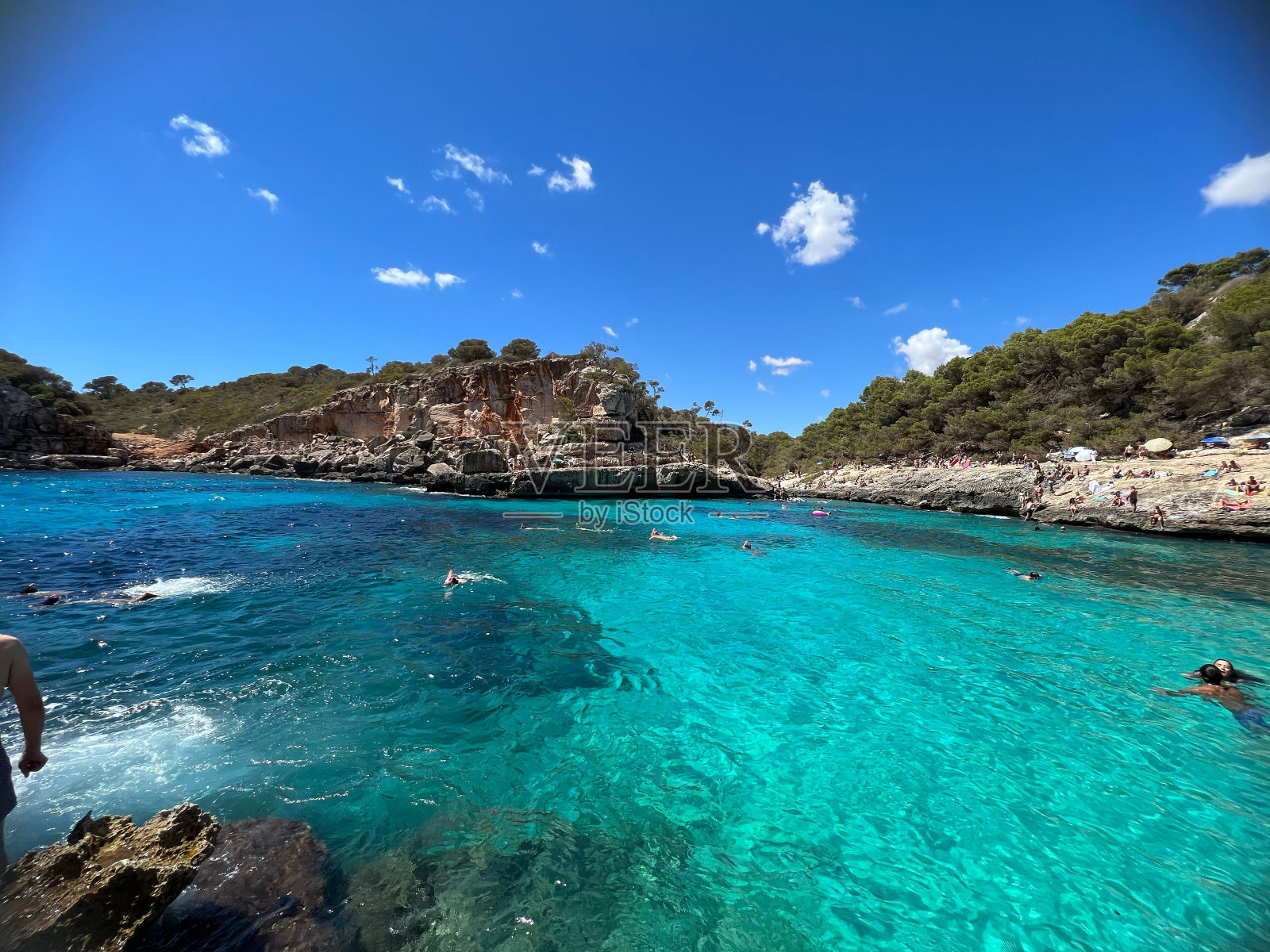 清澈的大海和岸边的岩石山脉照片摄影图片