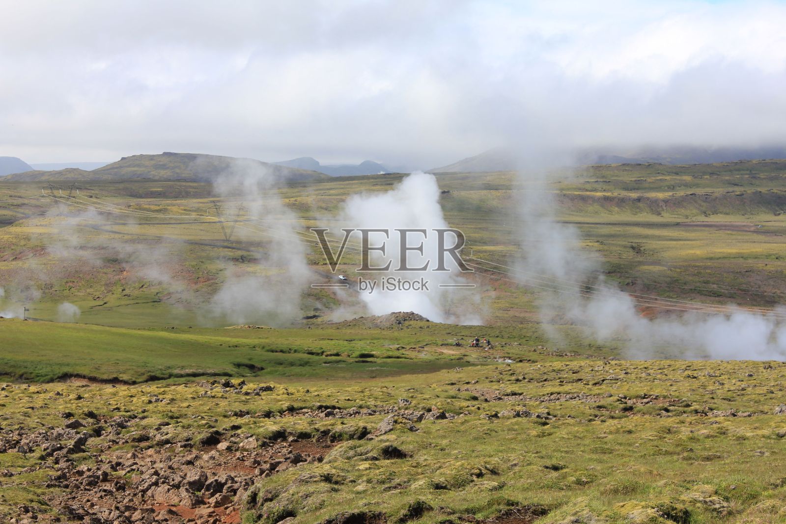从冰岛赫维拉格迪的绿色岩石山上看到的温泉蒸汽照片摄影图片