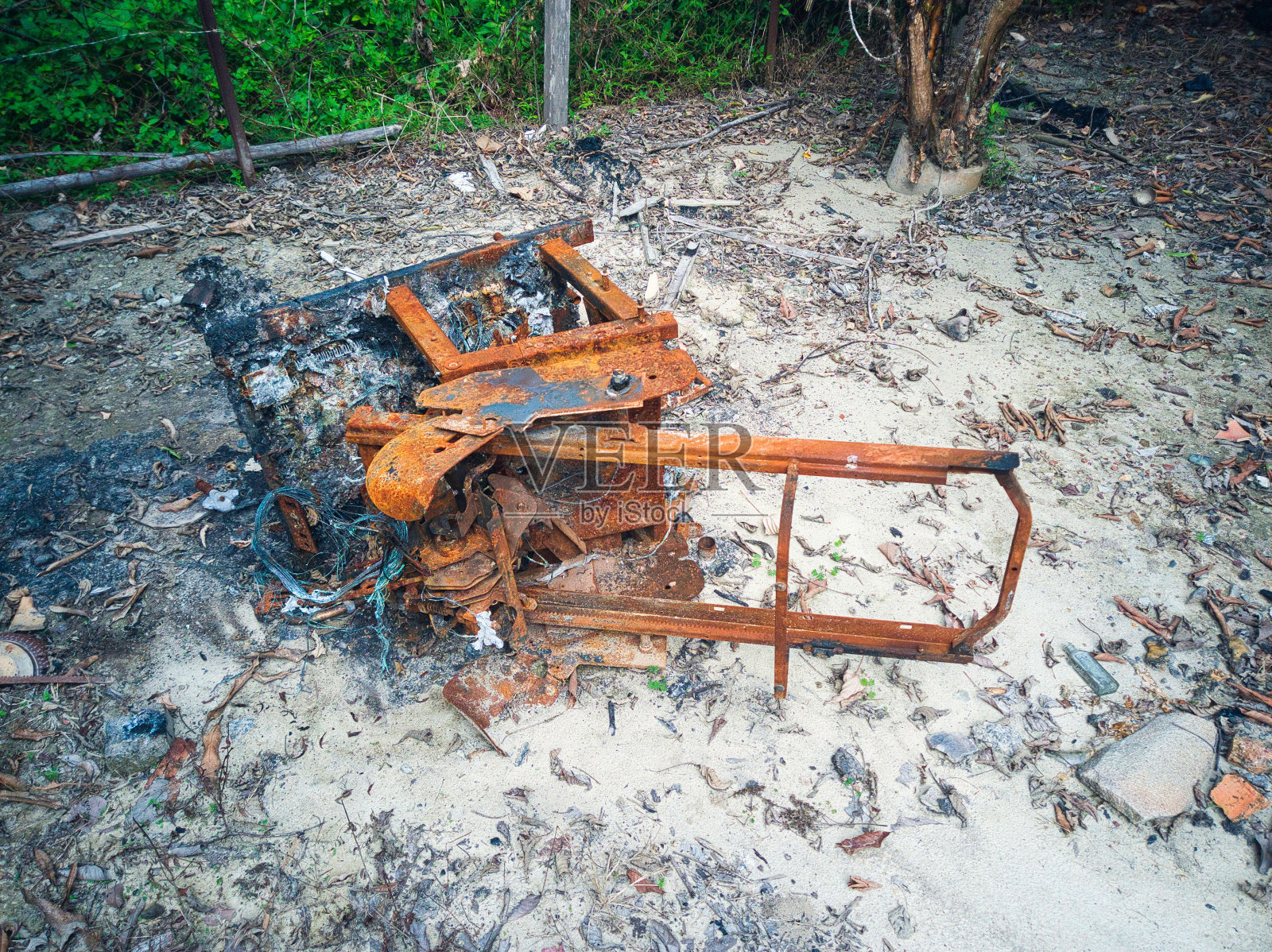 高角度拍摄的烧伤和生锈的按摩椅在一堆灰烬照片摄影图片