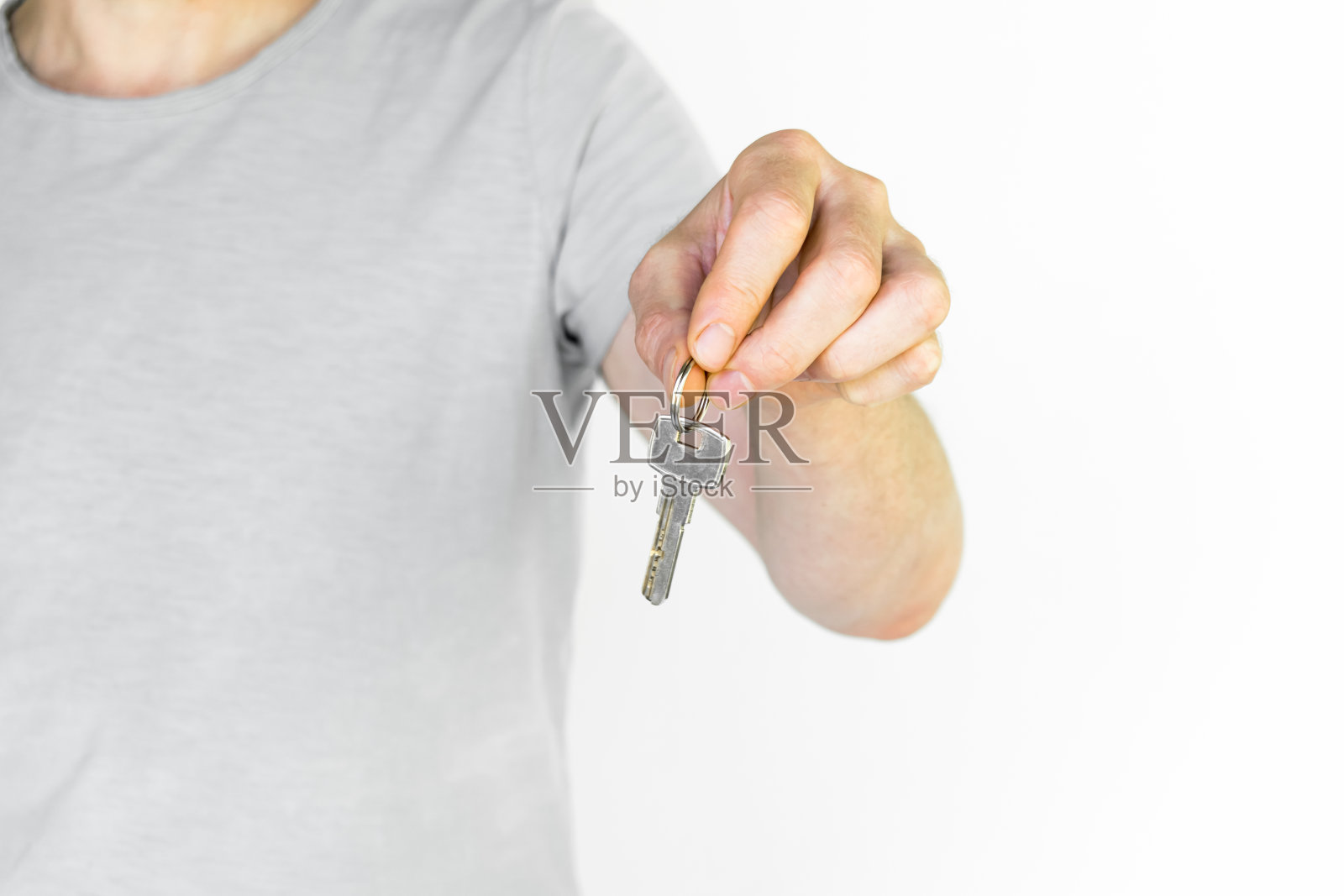 一个穿灰色t恤的男人给了我一把钥匙照片摄影图片