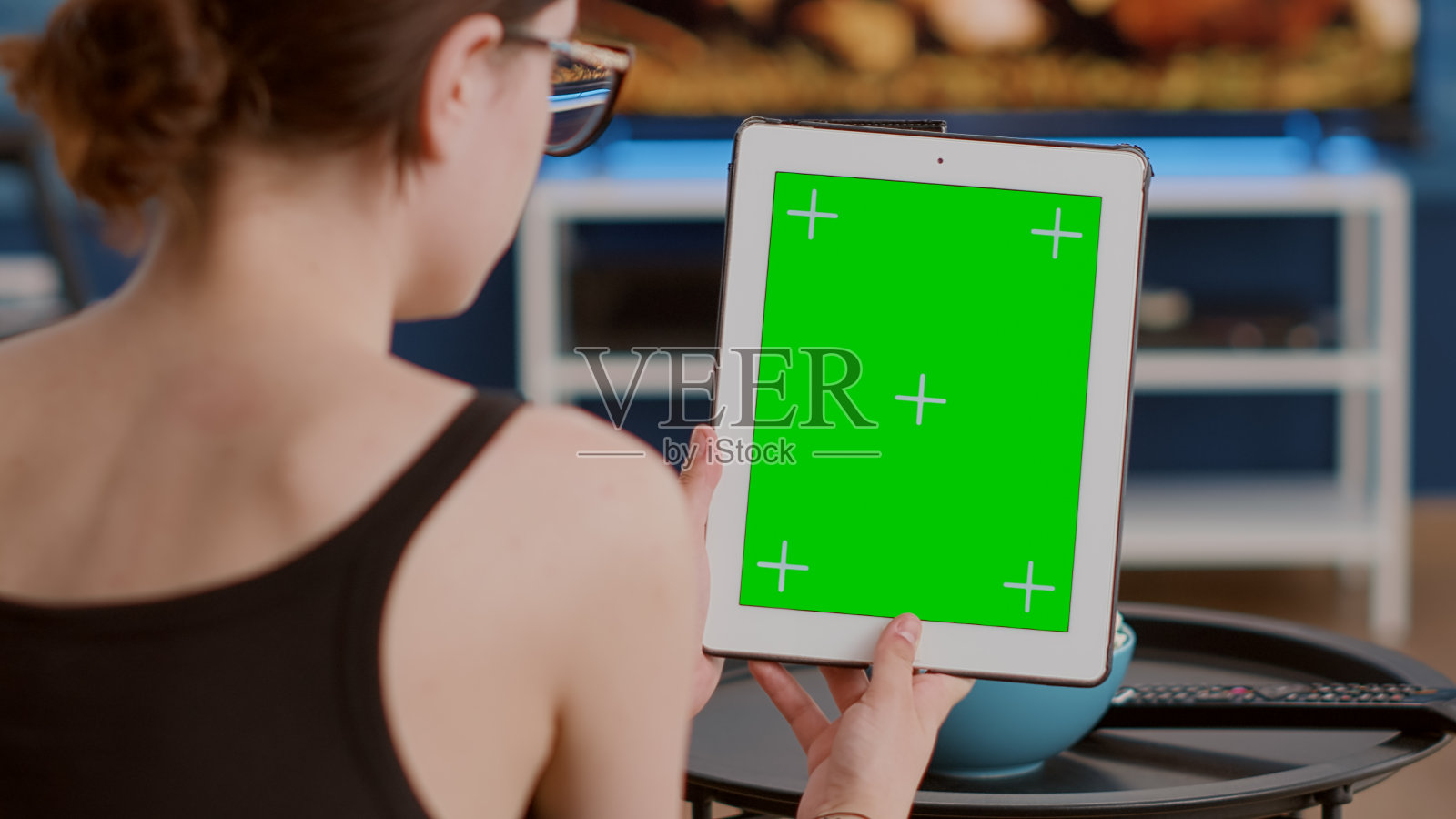 在在线会议或群视频通话中，年轻女子手持绿色屏幕的垂直数字平板电脑的特写照片摄影图片