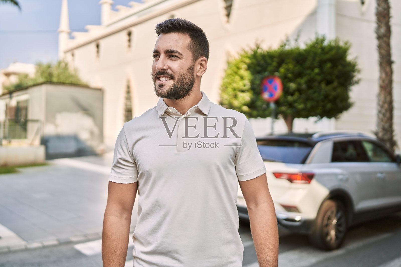 年轻的西班牙男子微笑自信地走在街上照片摄影图片