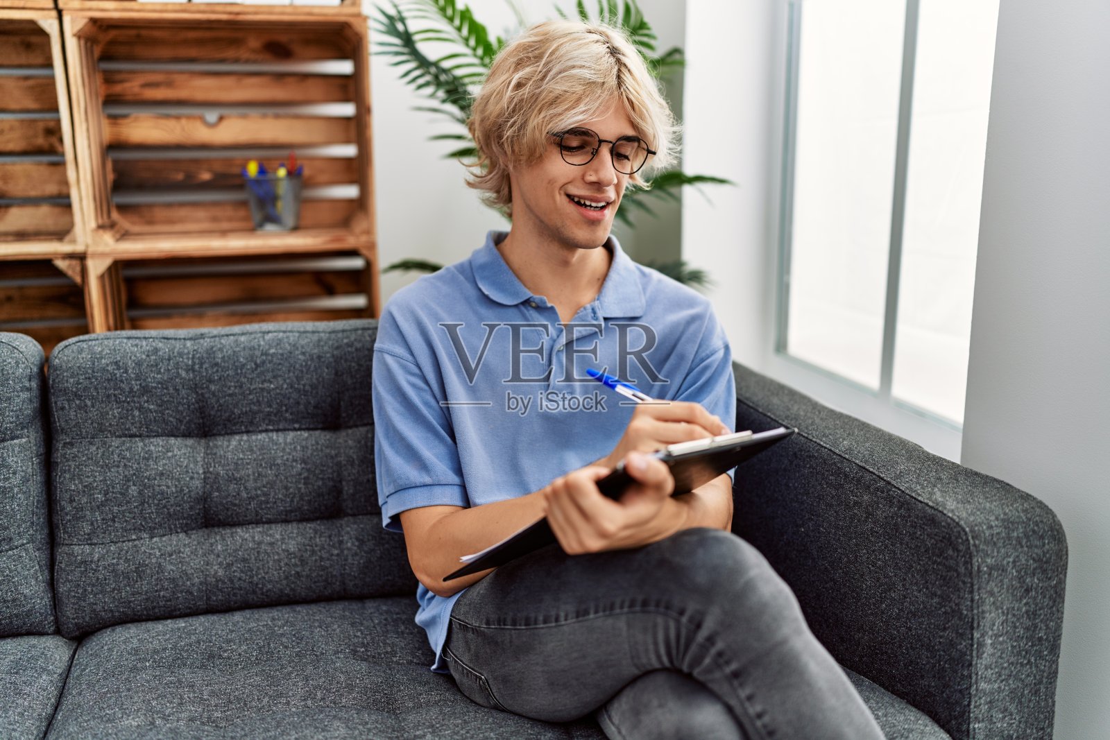 年轻的金发男子心理学家在心理诊所写文件照片摄影图片