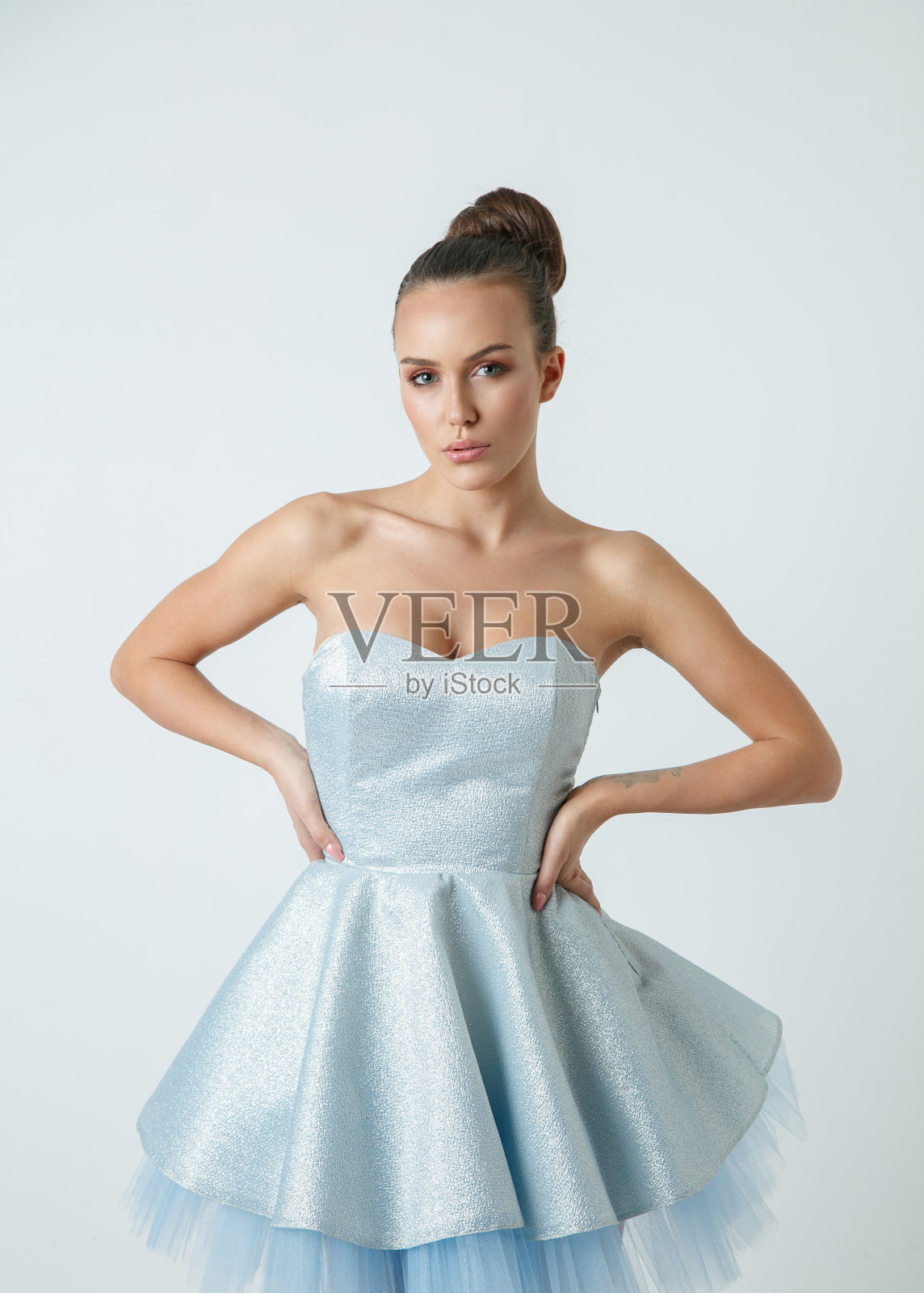 美丽的年轻黑发女子的肖像与发髻穿着银蓝色无肩带迷你连衣裙照片摄影图片