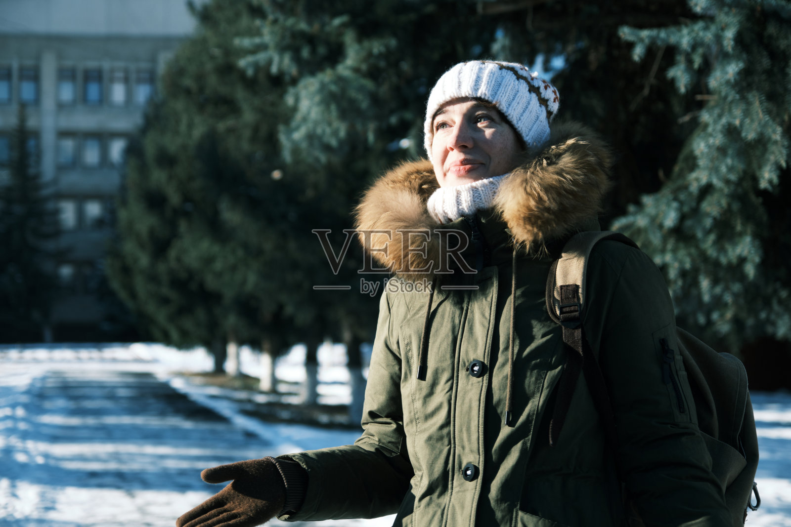 一个女人走在冬天小镇的大街上，带着幸福的微笑向别人打招呼照片摄影图片