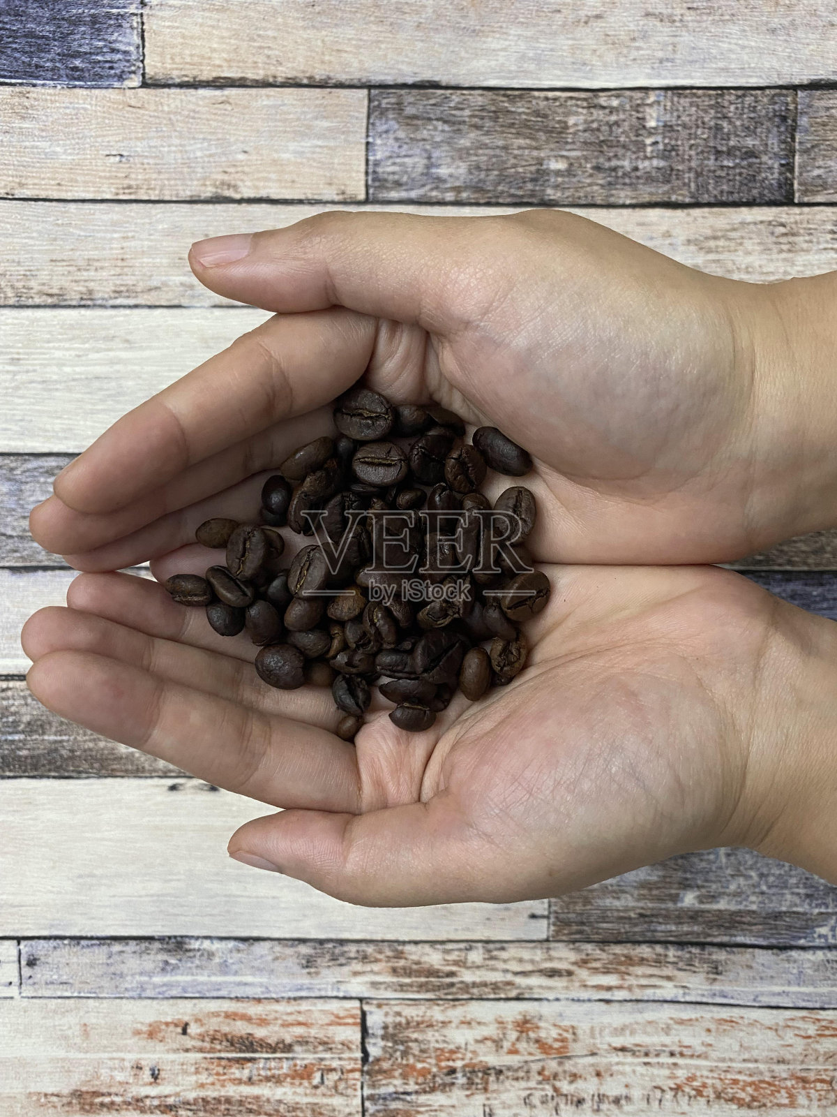 亚洲妇女手持咖啡豆在木制纹理背景。照片摄影图片