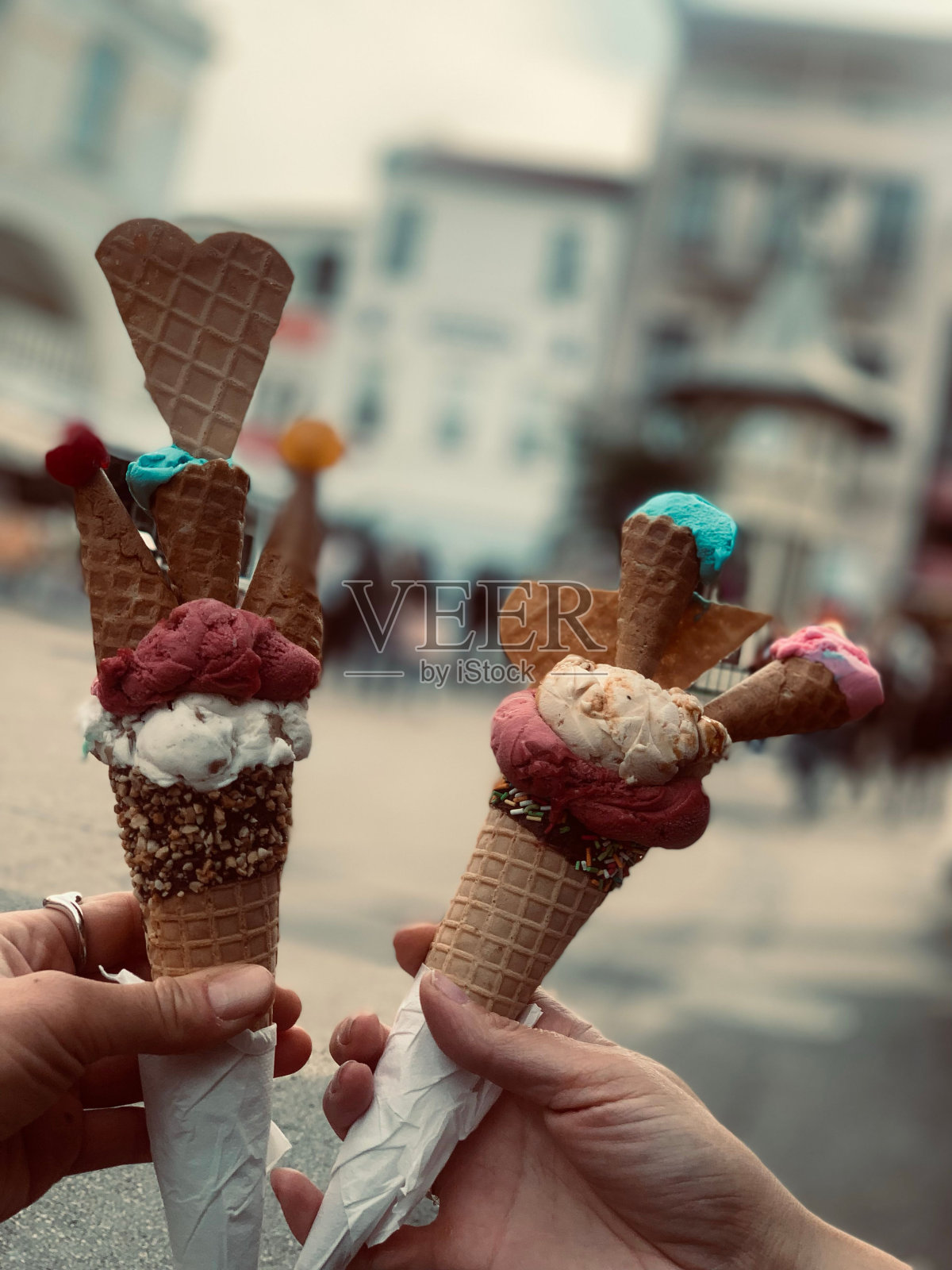 垂直特写镜头，人们拿着两个创意丰富的蛋卷冰淇淋照片摄影图片