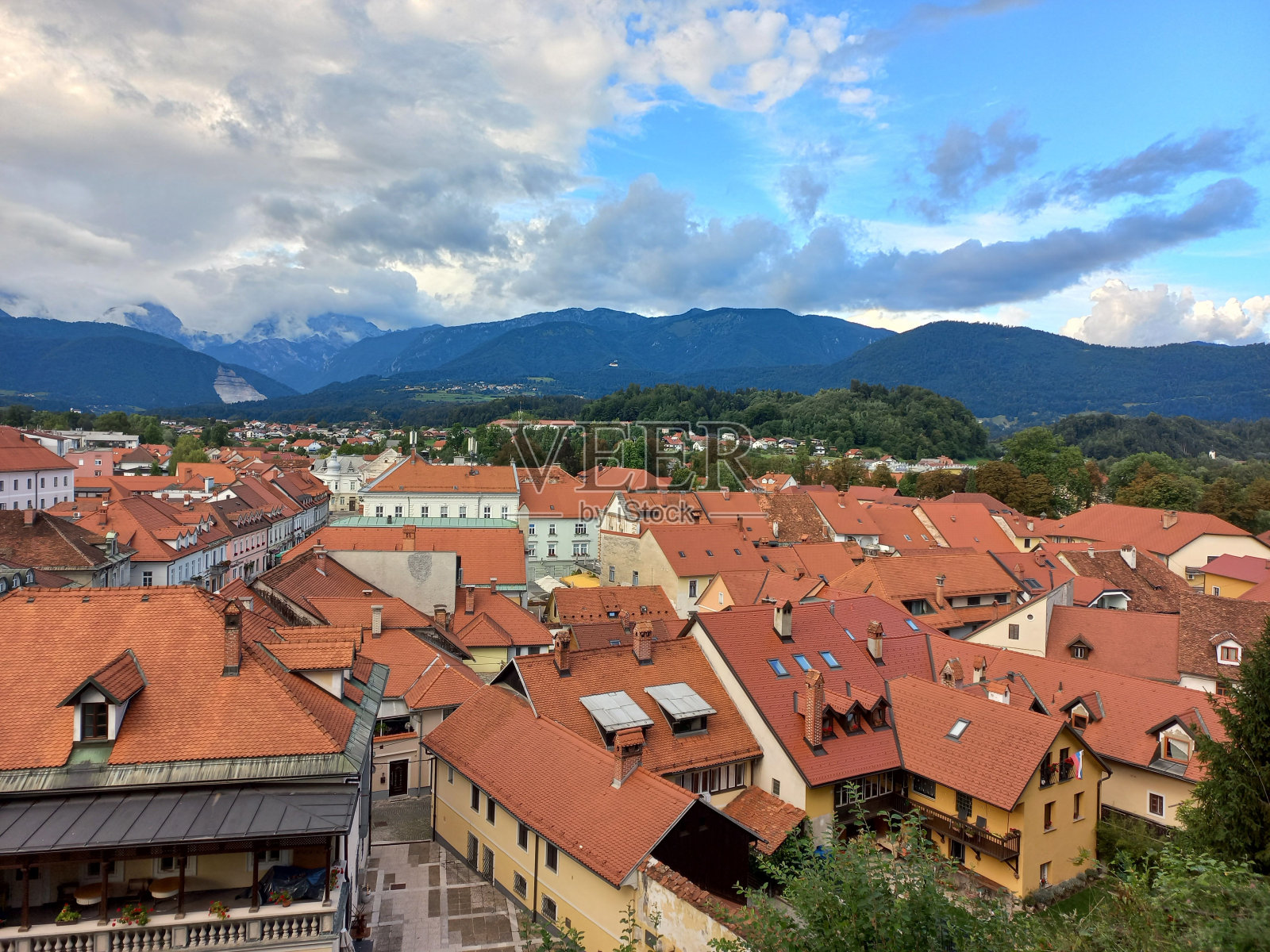 在阴沉的天空下，红色屋顶的密集建筑被山林包围照片摄影图片