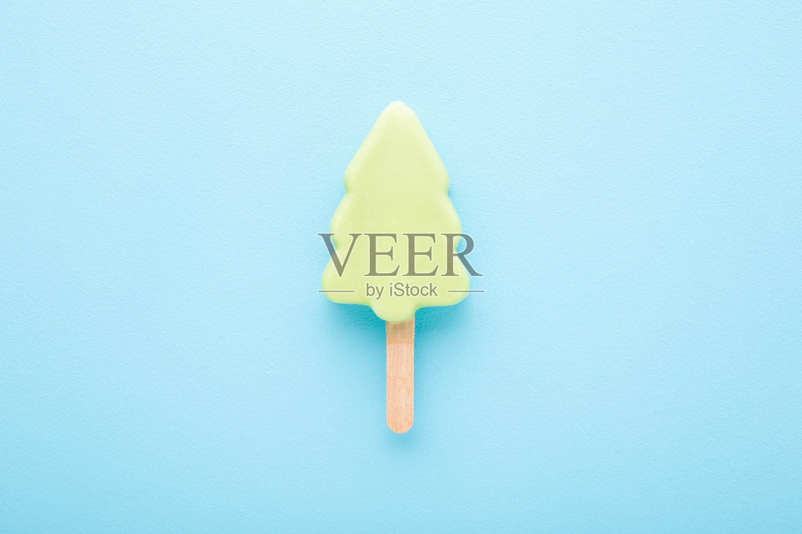 浅绿色云杉形状的冰淇淋，有开心果或薄荷口味。浅蓝色的桌面背景。柔和的颜色。特写镜头。在圣诞节的时候，冬天的冷甜点。自顶向下视图。照片摄影图片