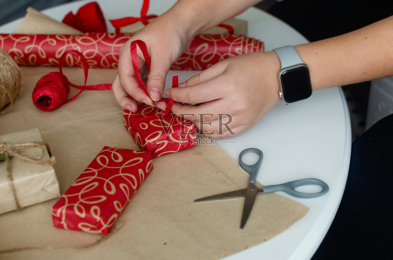 用牛皮纸包装圣诞礼盒的过程。为假期做准备。照片摄影图片