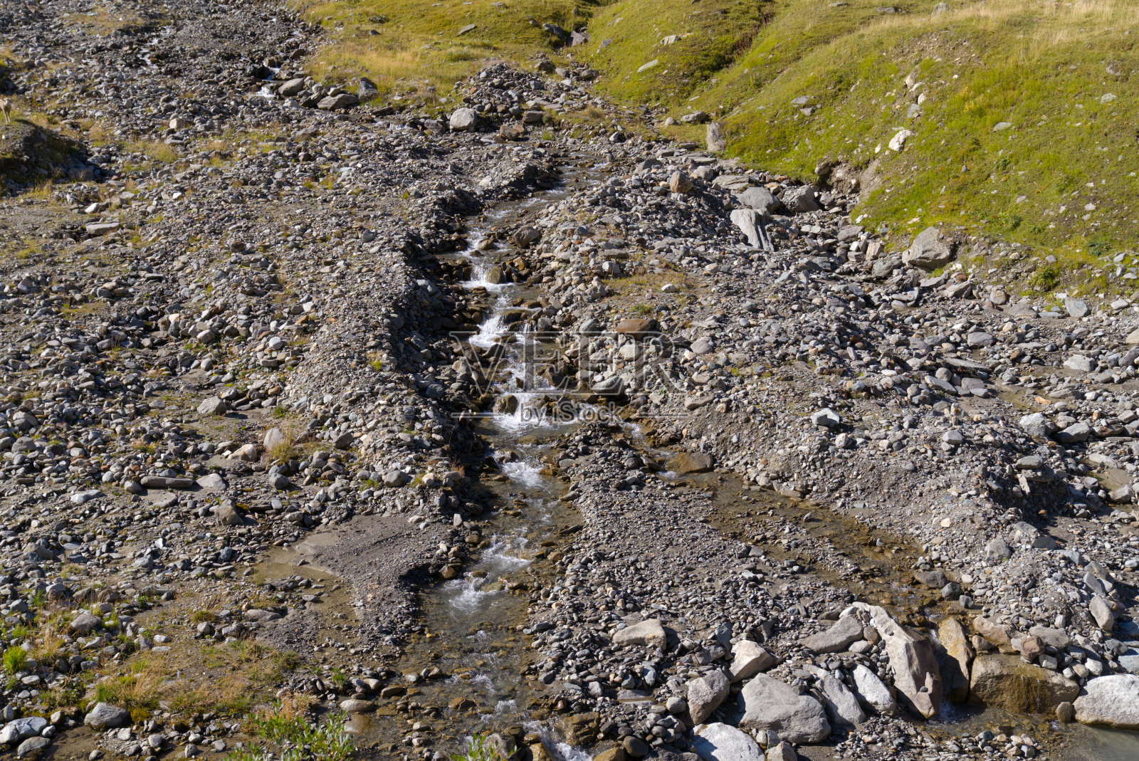 在一个阳光明媚的夏末的一天，瑞士阿尔卑斯山的瑞士山口Furkapass地区的岩石和草地风景。照片摄影图片