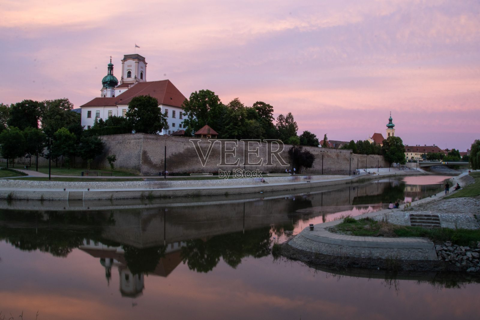 匈牙利Gyor的一座古老建筑在粉红色夕阳下映照在运河上的美丽照片照片摄影图片