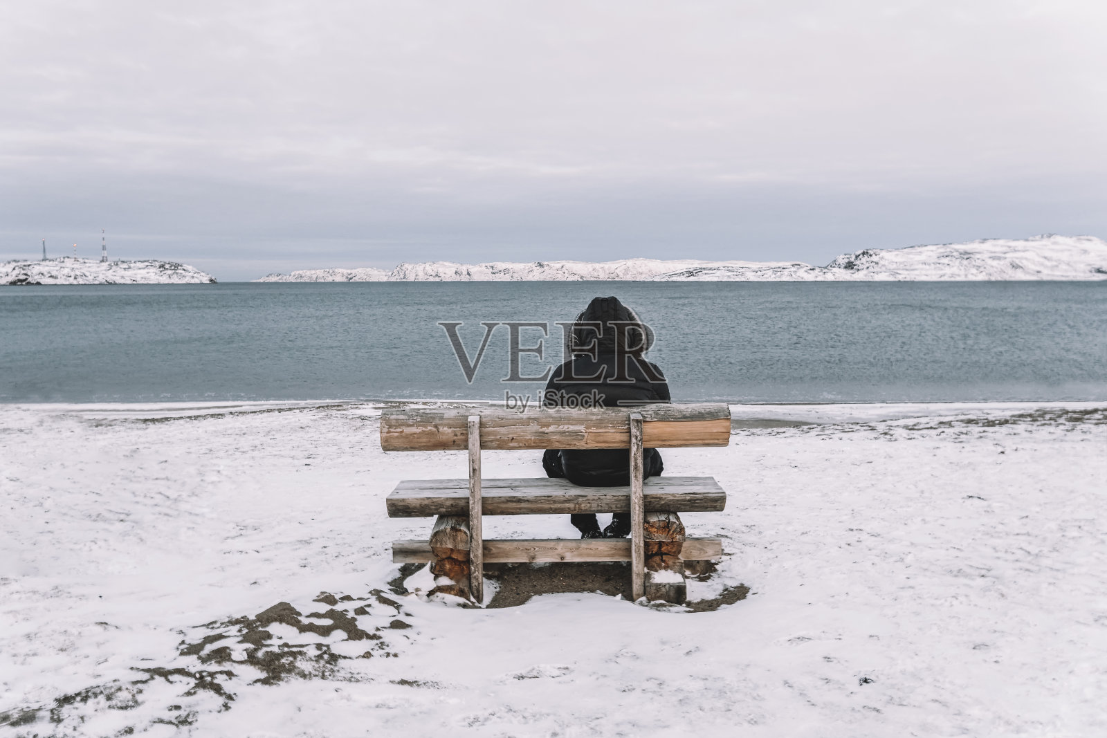 孤独和孤独的概念。寒冷的冬季景观。在冬天的海滩上，沿着人与空板凳照片摄影图片