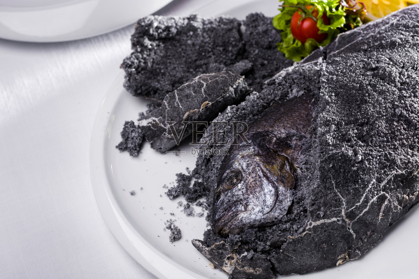 多拉多鱼配灰盐、柠檬、圣女果和沙拉，白色盘中，浅色背景，横向构图照片摄影图片