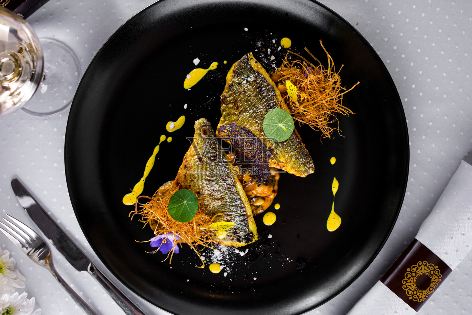 油炸多拉多片与红薯，蕾丝片，黄酱，装饰在一个圆形的黑色盘子，一杯酒和餐具。水平方向照片摄影图片