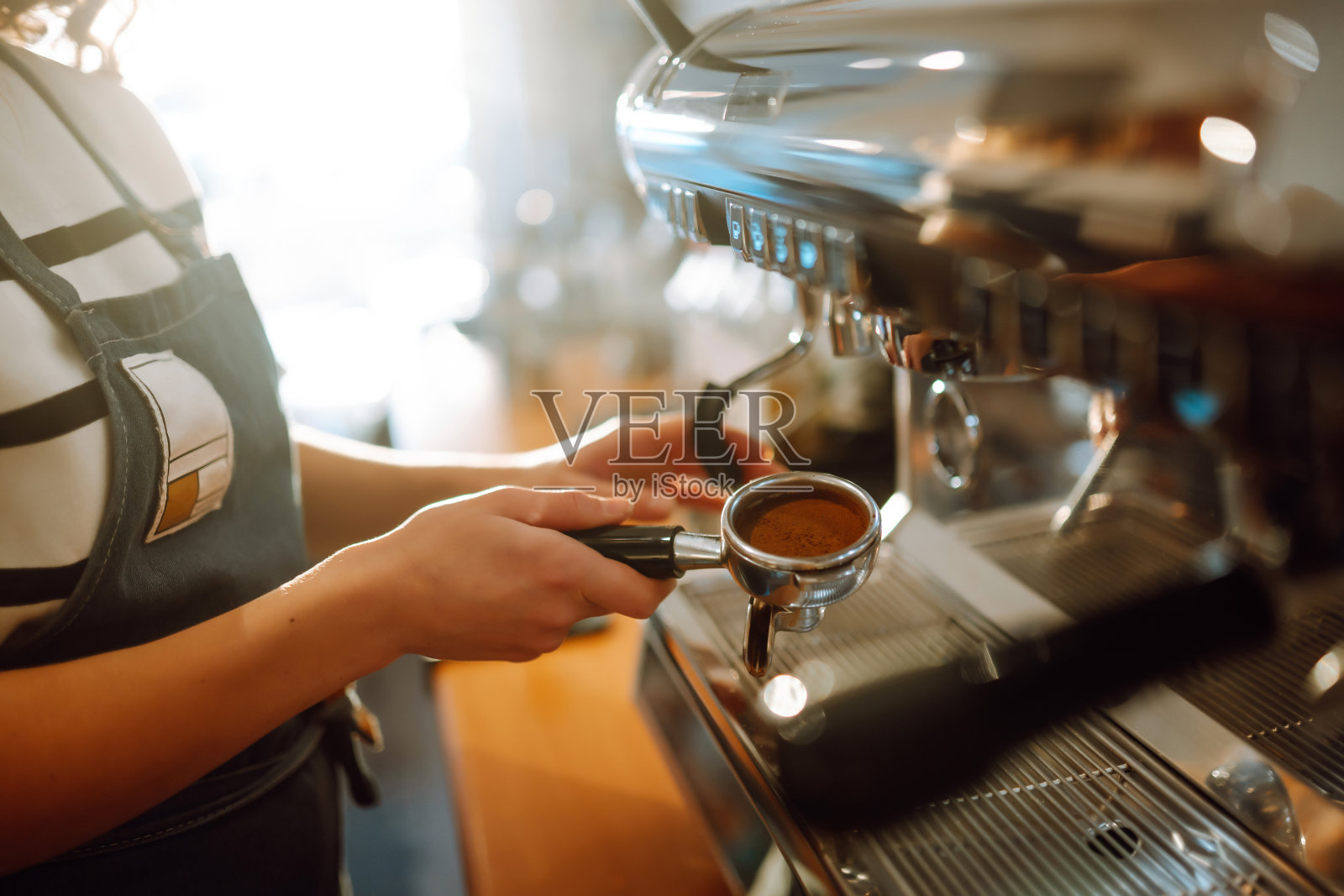 咖啡师拿着杯子，从咖啡机中取出新鲜的咖啡。照片摄影图片