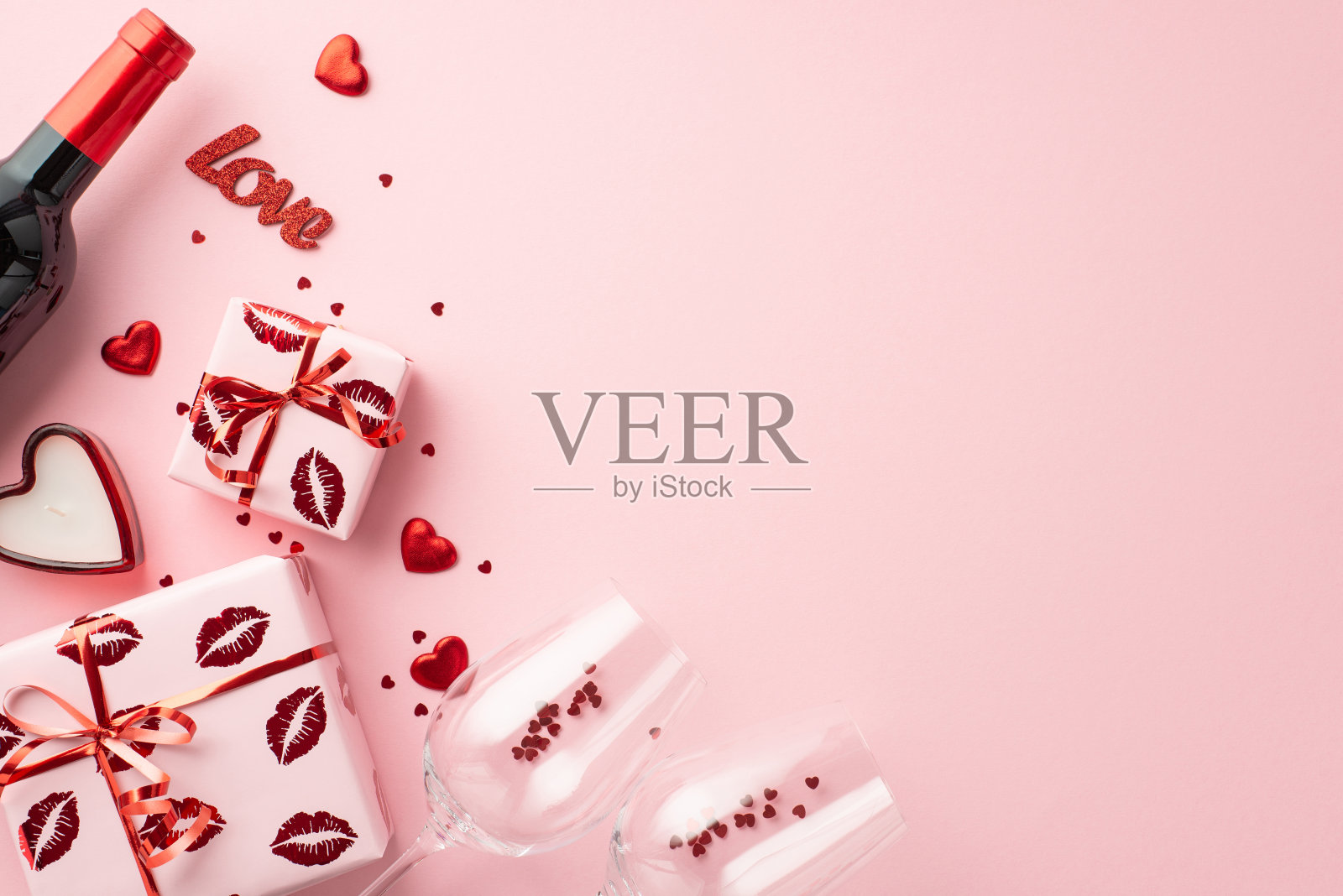 情人节的概念。顶部视图照片礼盒酒瓶两个玻璃杯与五彩纸屑心形蜡烛和铭文爱在孤立的粉彩粉红色背景与复制空间照片摄影图片