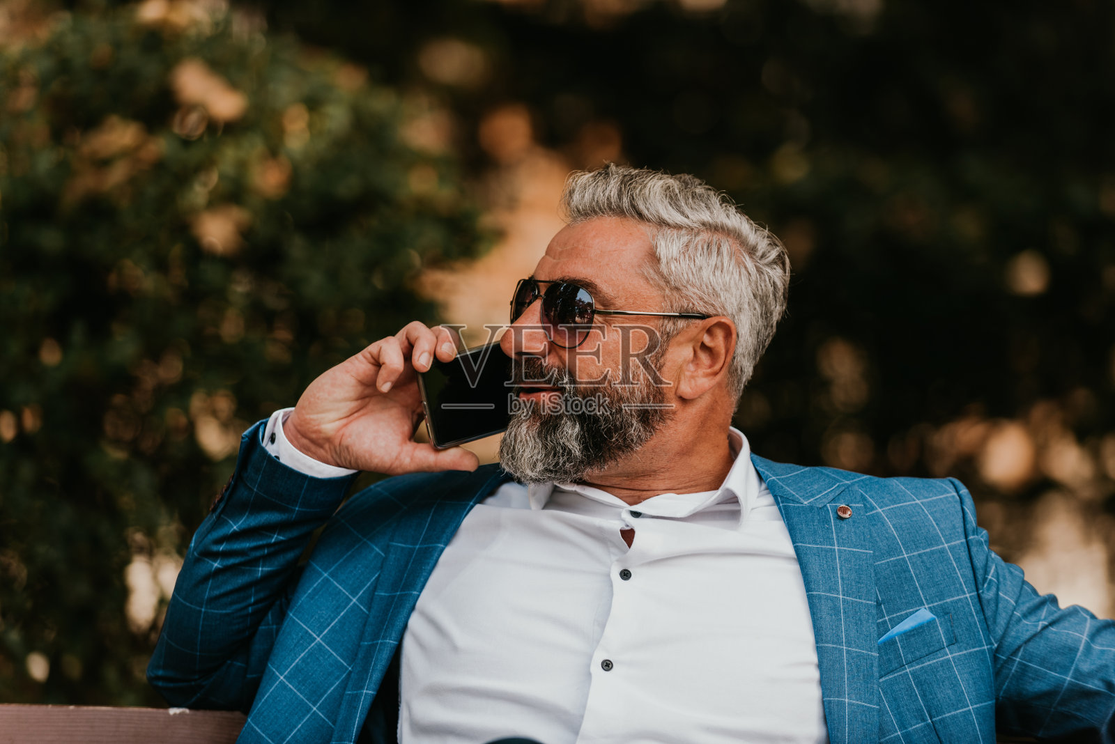 现代成熟商人坐在长椅上使用智能手机进行在线会议照片摄影图片