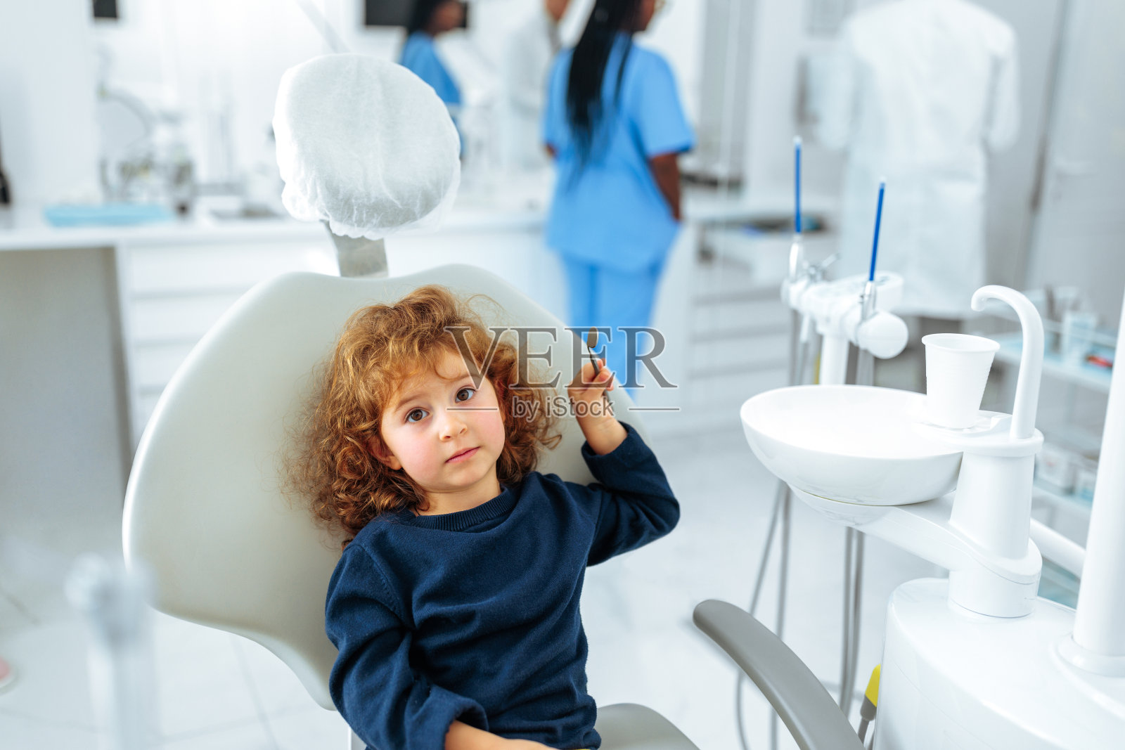 可爱的小孩坐在牙医的椅子上。照片摄影图片