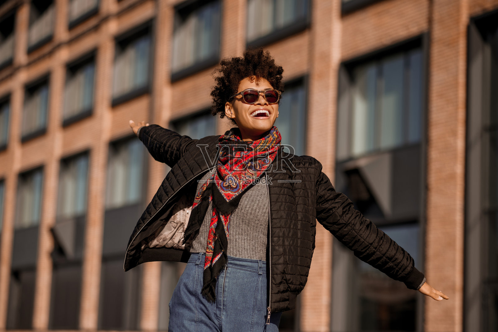 一个黑皮肤的女孩戴着墨镜走在街上，心情愉快照片摄影图片