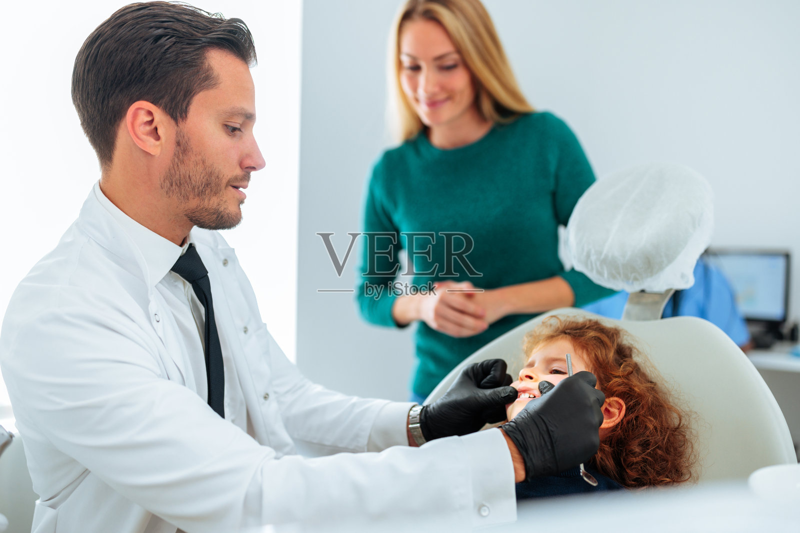 正畸医生在办公室检查儿童牙齿。照片摄影图片