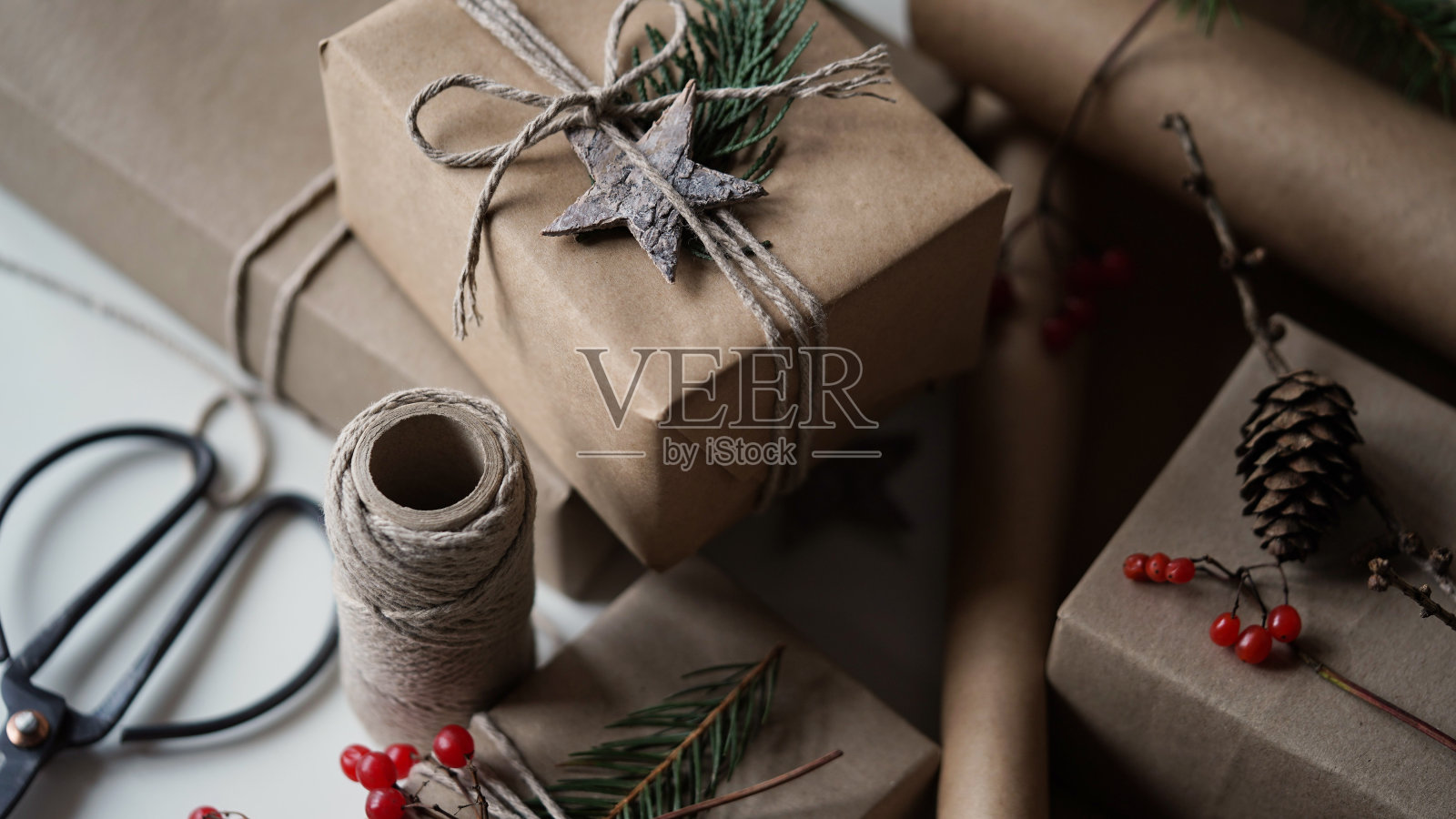 零浪费和环保的圣诞概念。给家人和朋友的圣诞和新年礼物用牛皮纸、绳子和天然植物装饰、树枝、球果、浆果、星星包装。有选择性的重点。照片摄影图片