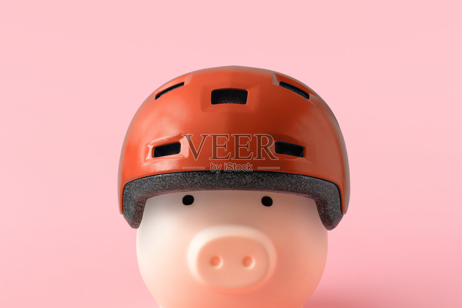 粉红背景上红色头盔的存钱罐。财务保障和保险理念照片摄影图片