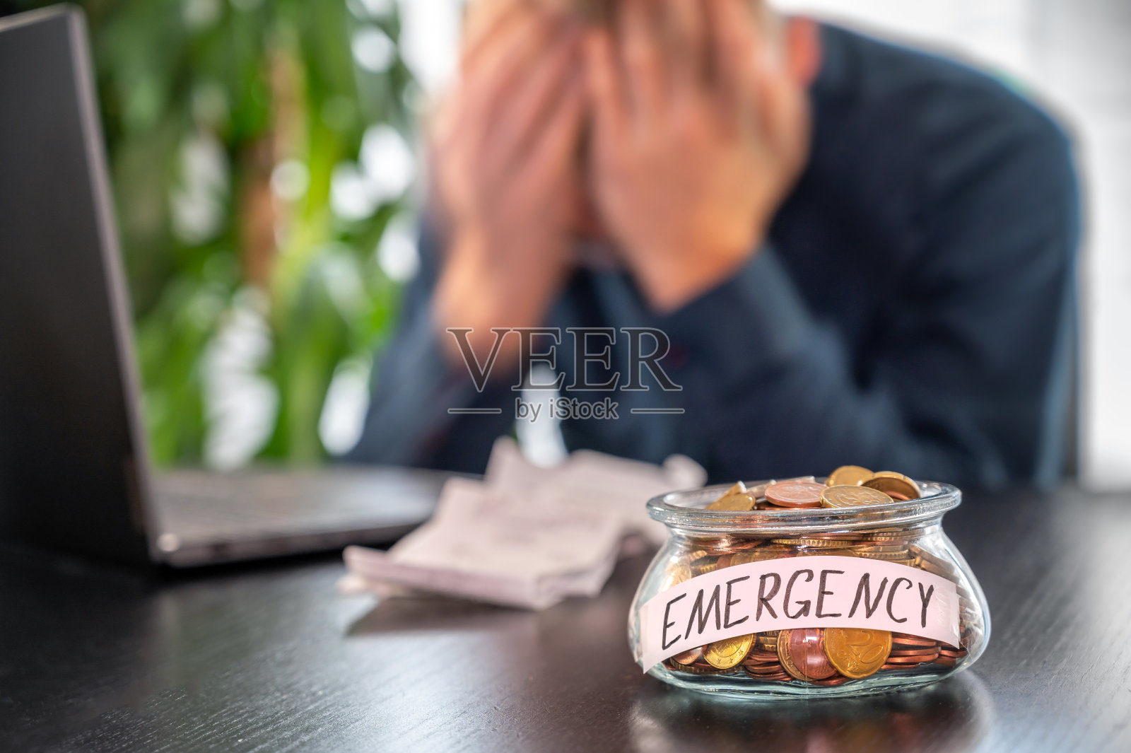 一个绝望的男人和一个装满硬币的罐子上面用德语写着"紧急照片摄影图片