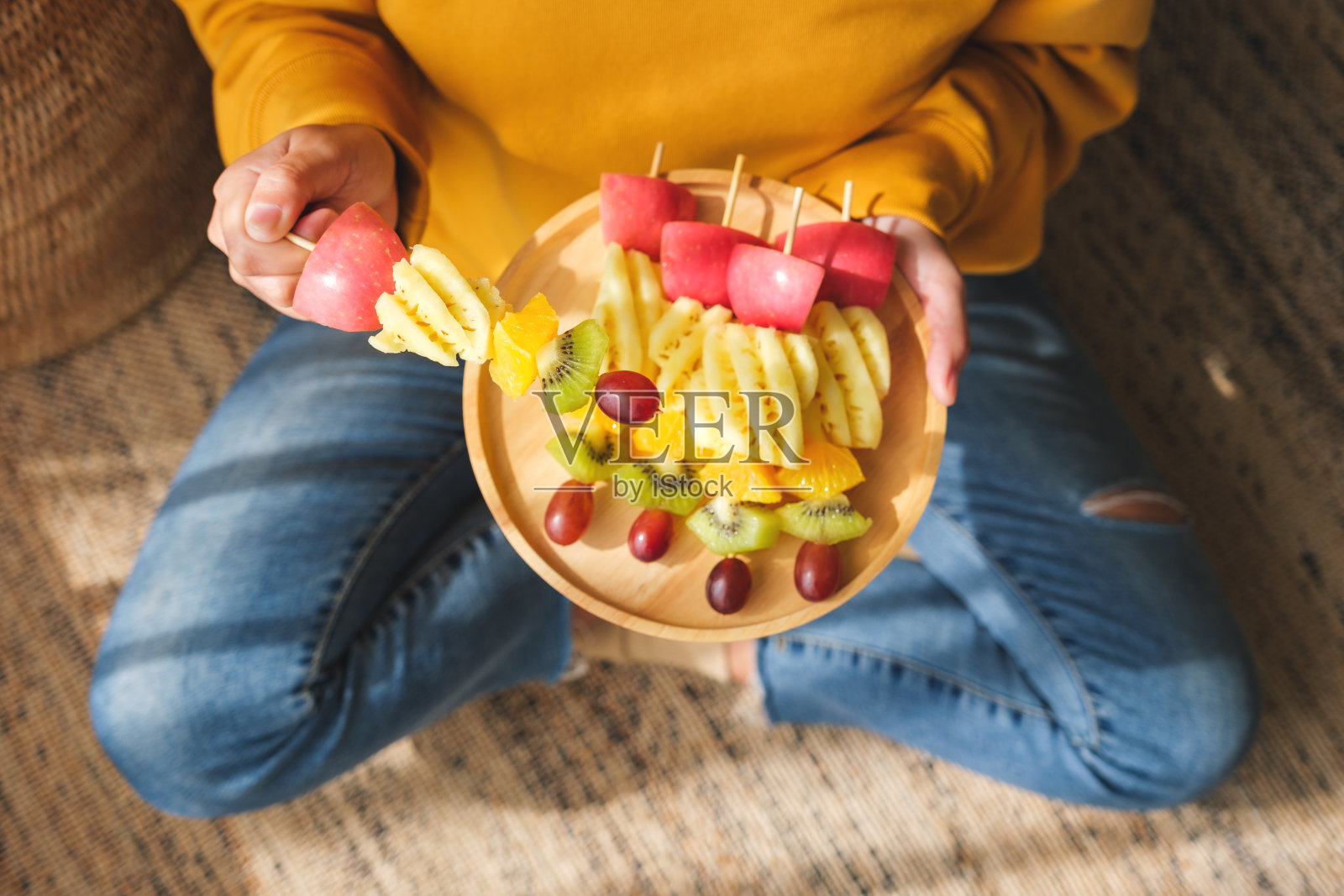 俯视图的形象，一个女人拿着一盘新鲜混合水果串木盘照片摄影图片