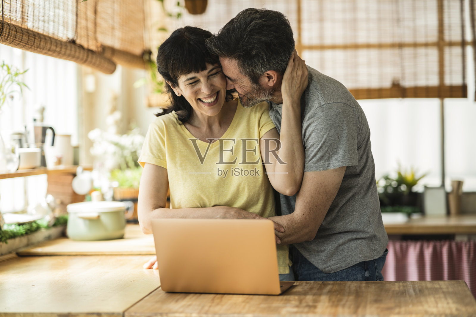 幸福的西班牙夫妇在厨房远程办公时相互拥抱和支持照片摄影图片