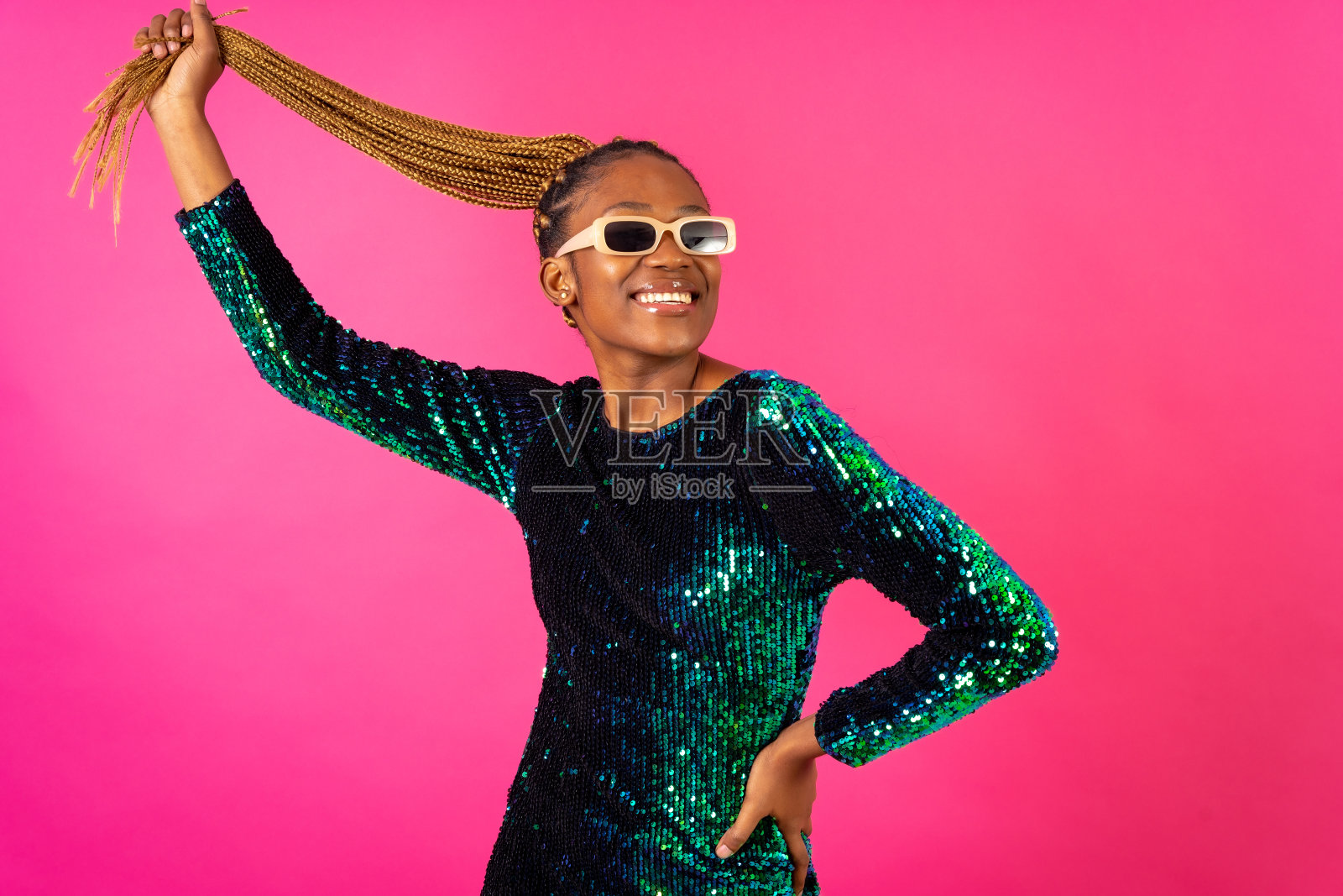 在粉红色的背景下，一个扎着辫子的黑人妇女在聚会上跳舞照片摄影图片