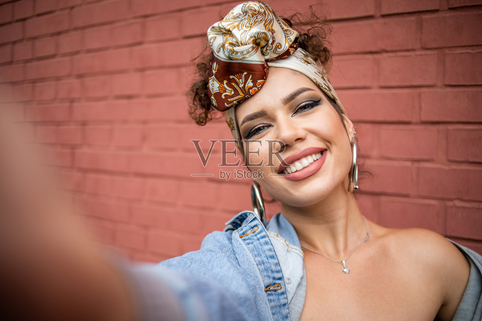 快乐的美丽时尚潮年轻女子微笑着在红砖墙前自拍照片摄影图片