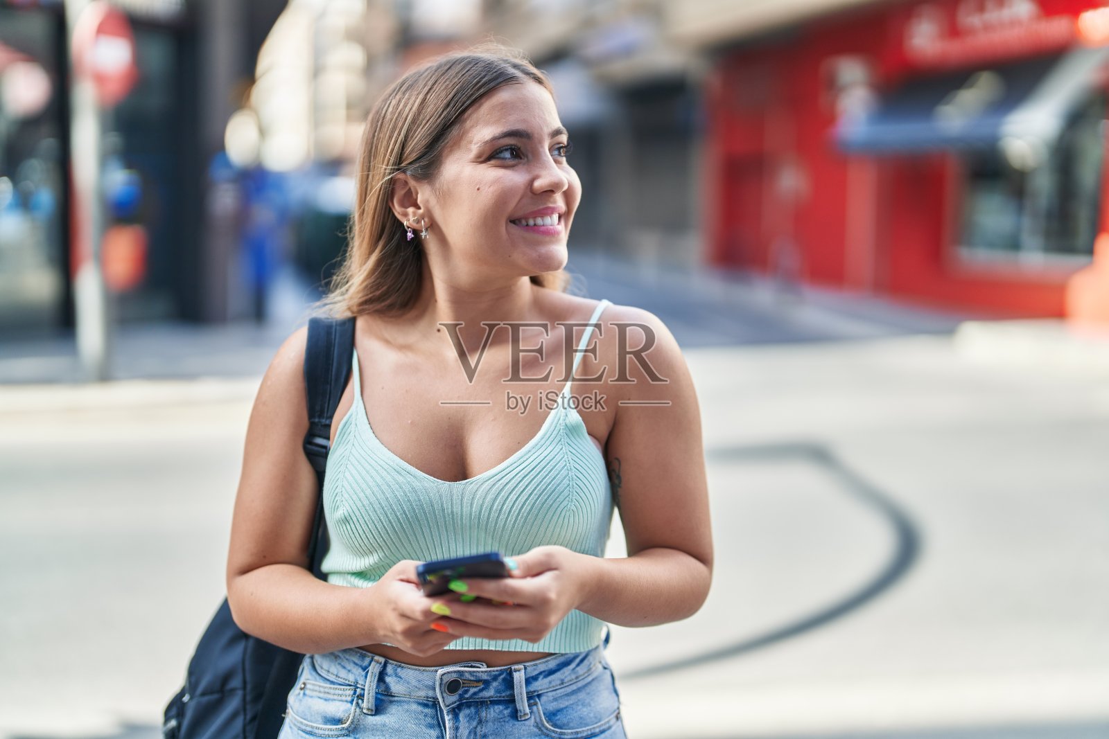 年轻美丽的西班牙女学生微笑自信地使用智能手机在街上照片摄影图片