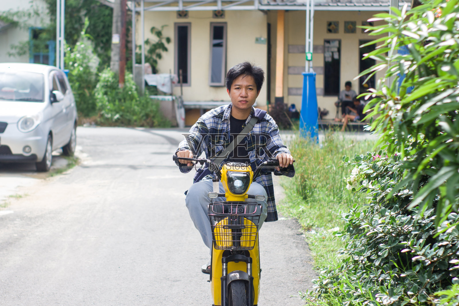 在居民区骑电动自行车的年轻人照片摄影图片