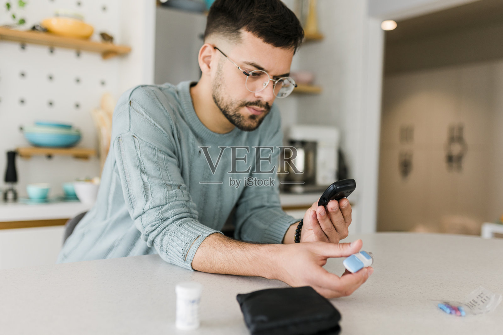 男子用手指上的柳叶刀通过血糖仪检查血糖水平，保健和医疗，糖尿病，血糖概念照片摄影图片