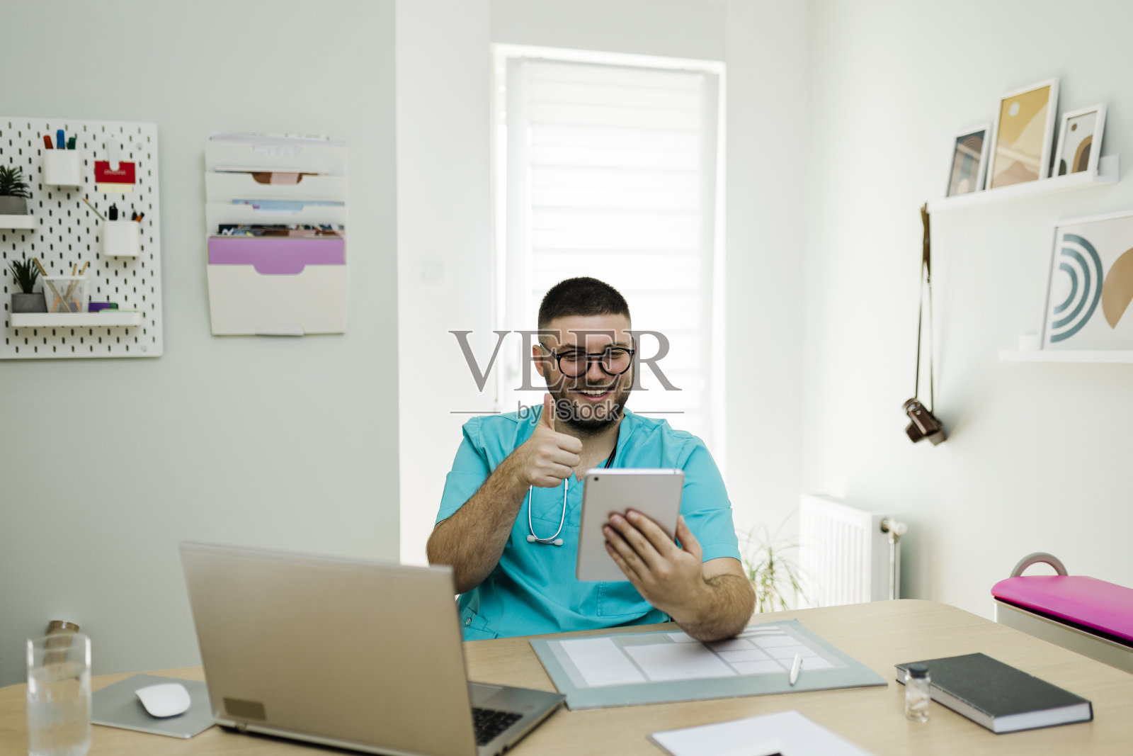 男医生使用他的数字平板电脑，在办公室工作照片摄影图片