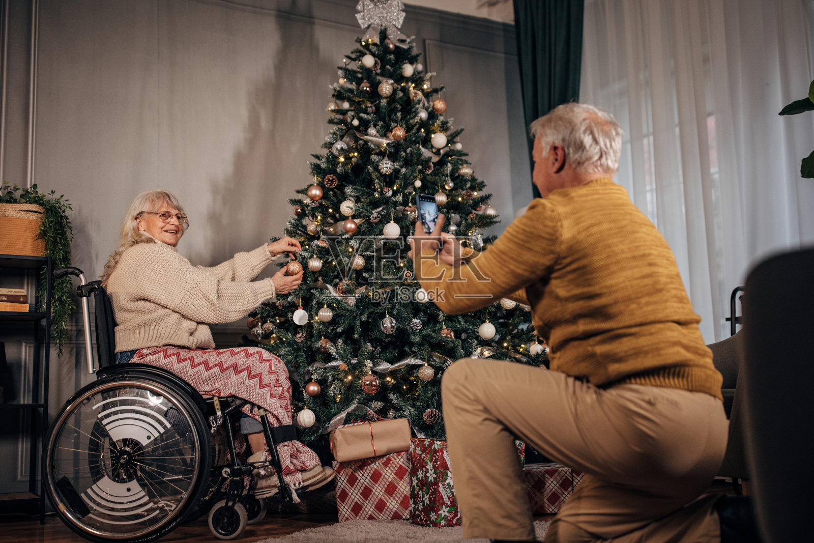 老夫妇在家里装饰圣诞树时拍照照片摄影图片