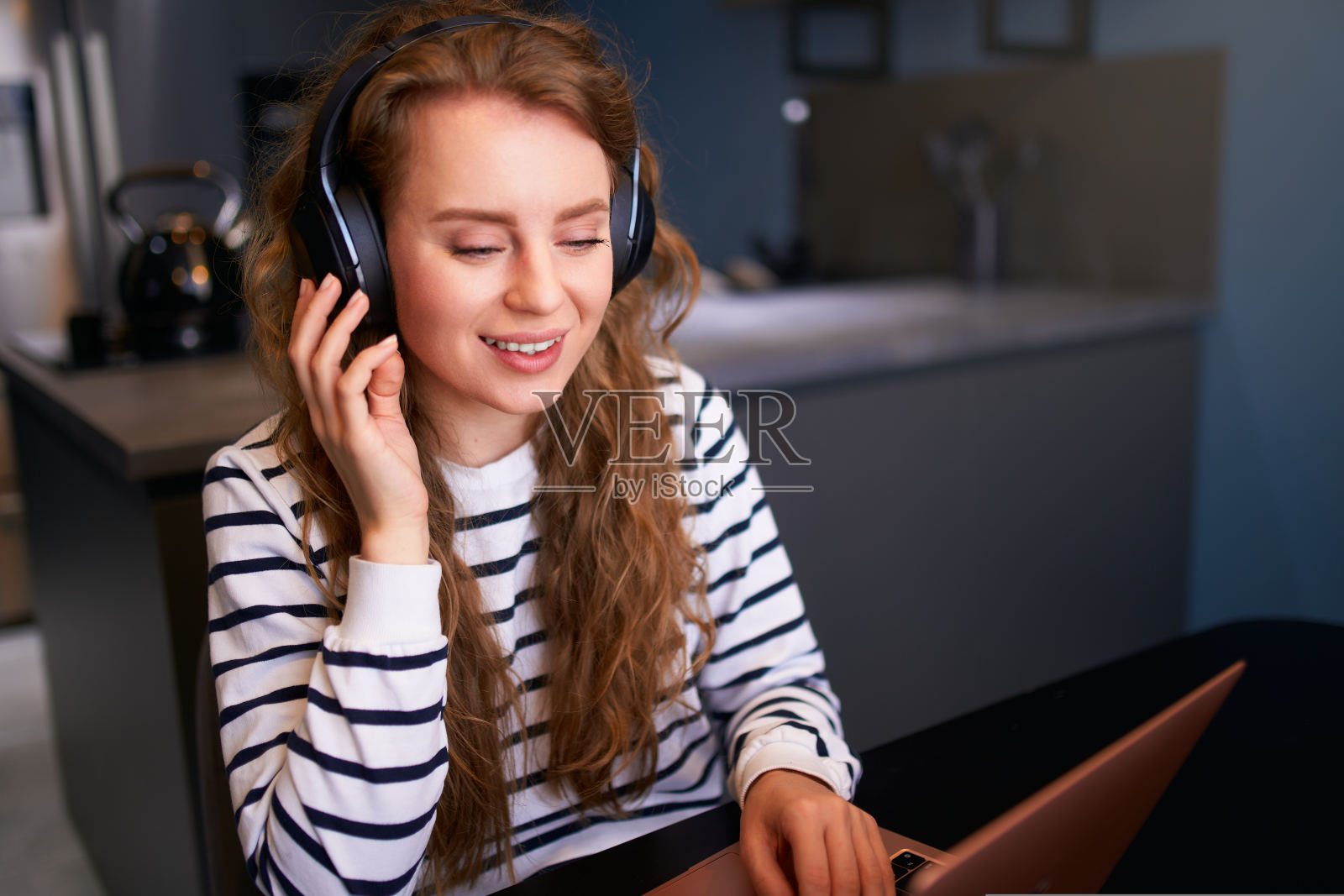 我是客户支持服务呼叫中心经理，在家工作。带着耳机的卷发女人，在笔记本电脑的网络摄像头上进行视频会议。年轻的女商人远程咨询商业伙伴照片摄影图片