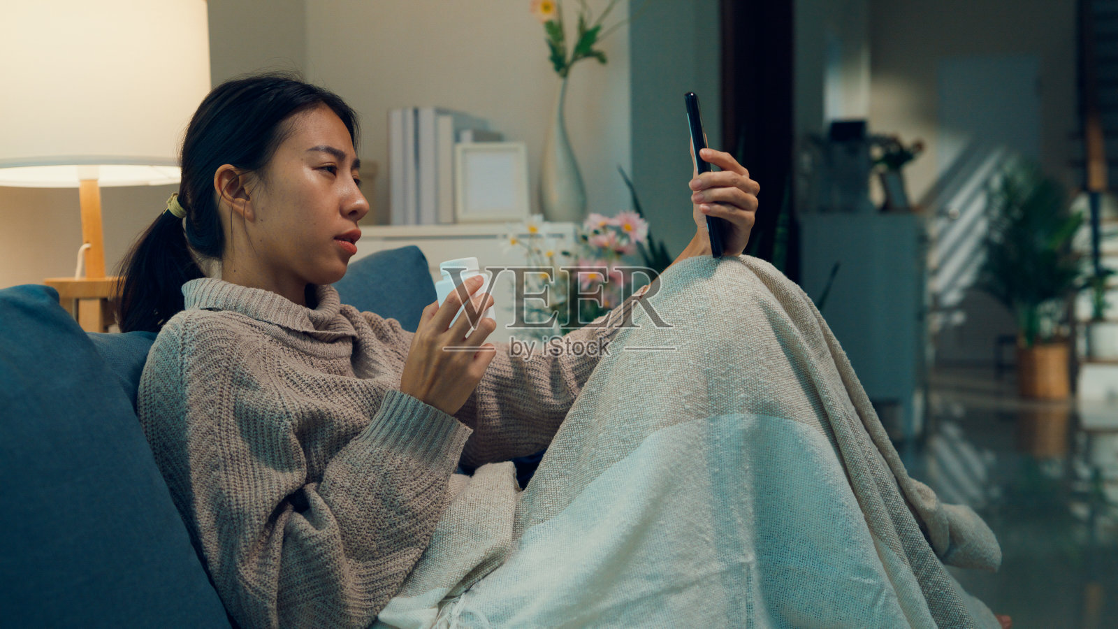 年轻的亚洲女孩患者在家中远程医疗在线服务医院的医疗app上通过手机视频电话向医生咨询用药剂量说明。照片摄影图片