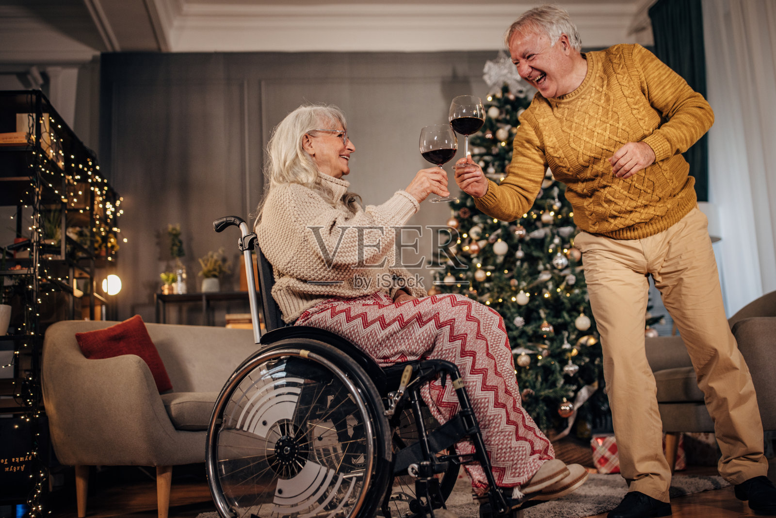 老夫妇在家里的圣诞树旁喝酒照片摄影图片