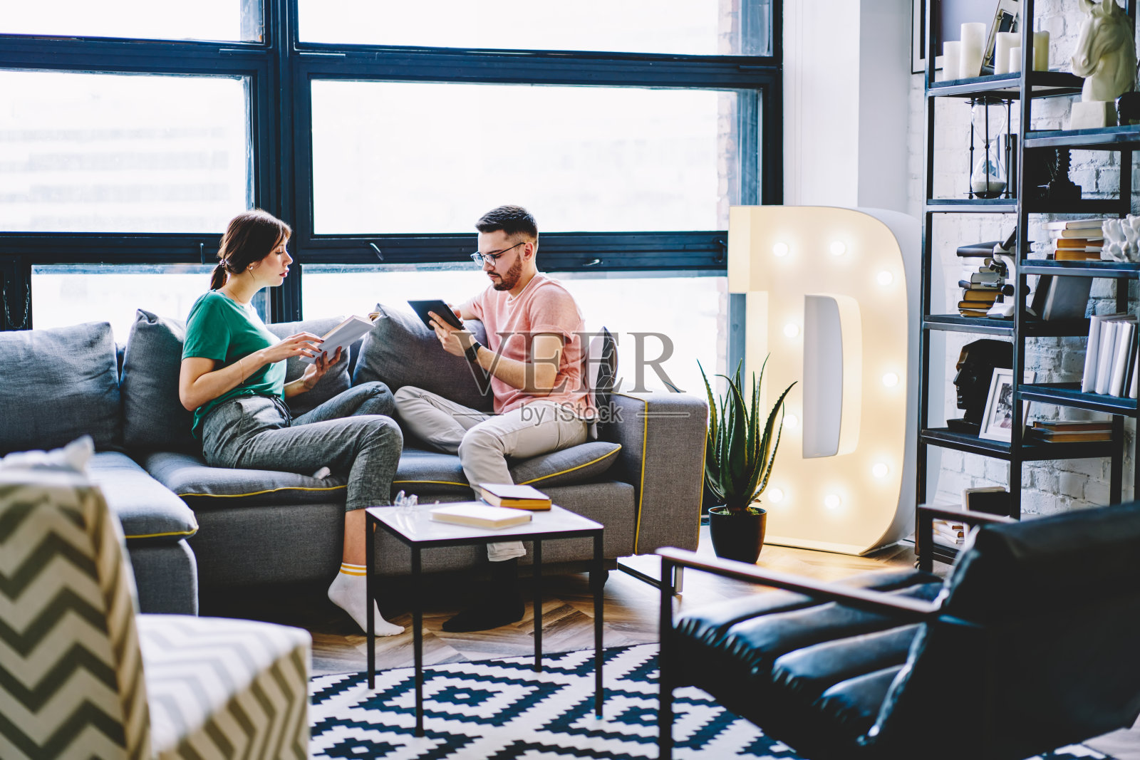 相爱的年轻夫妇一起坐在客厅的沙发上阅读书籍和使用触摸板，相爱的婚姻享受在家里休息谈论关系照片摄影图片