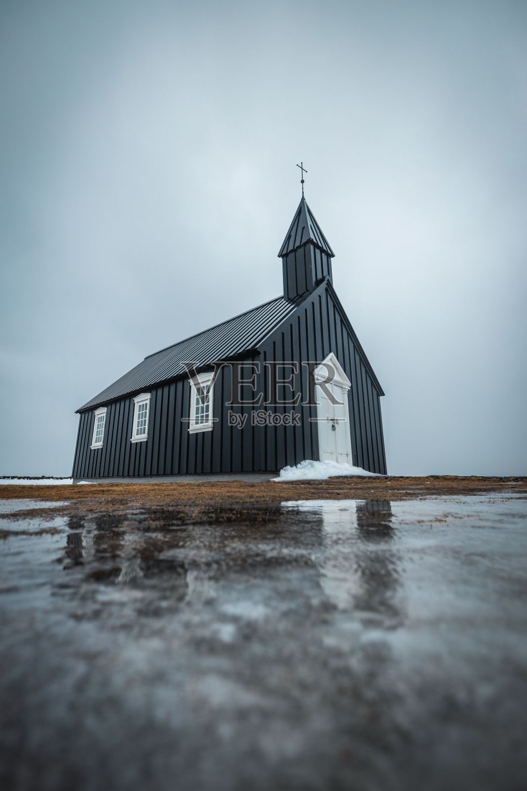 垂直拍摄的布达基尔加教堂和它的倒影在前面的水在布迪尔，冰岛照片摄影图片