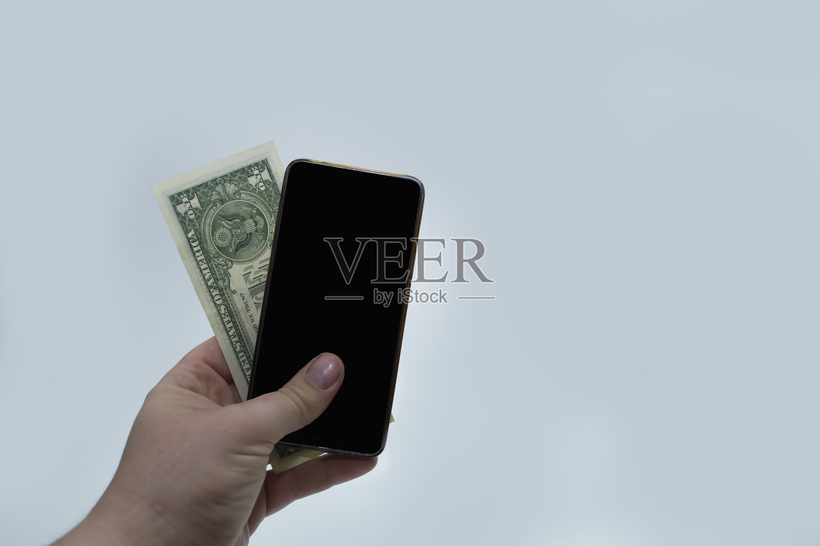 一个人保存一部手机和一美元，移动通信的费用，电话银行。照片摄影图片