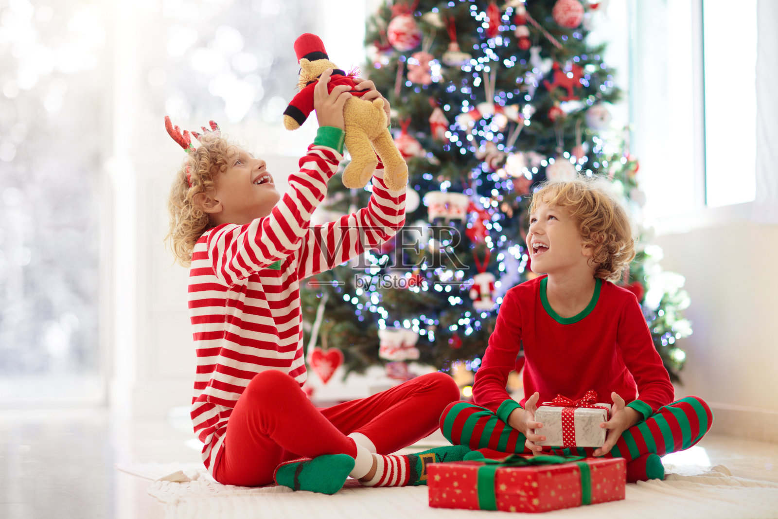 孩子在圣诞树旁。圣诞节孩子们在壁炉边照片摄影图片