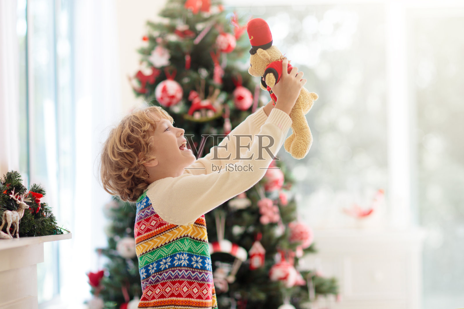 孩子在圣诞树旁。圣诞节孩子们在壁炉边照片摄影图片