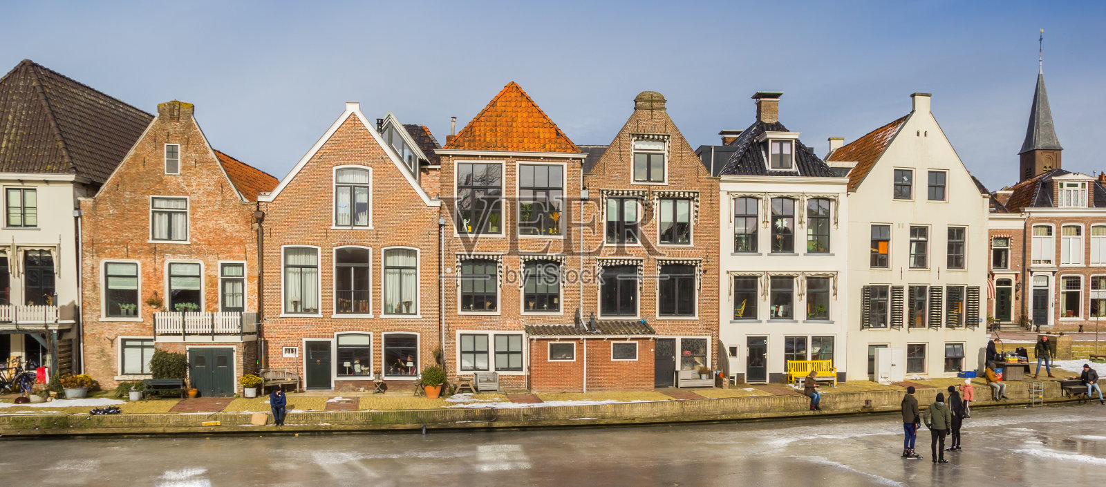 在冰冻的Dokkum运河上，一排历史悠久的房子照片摄影图片