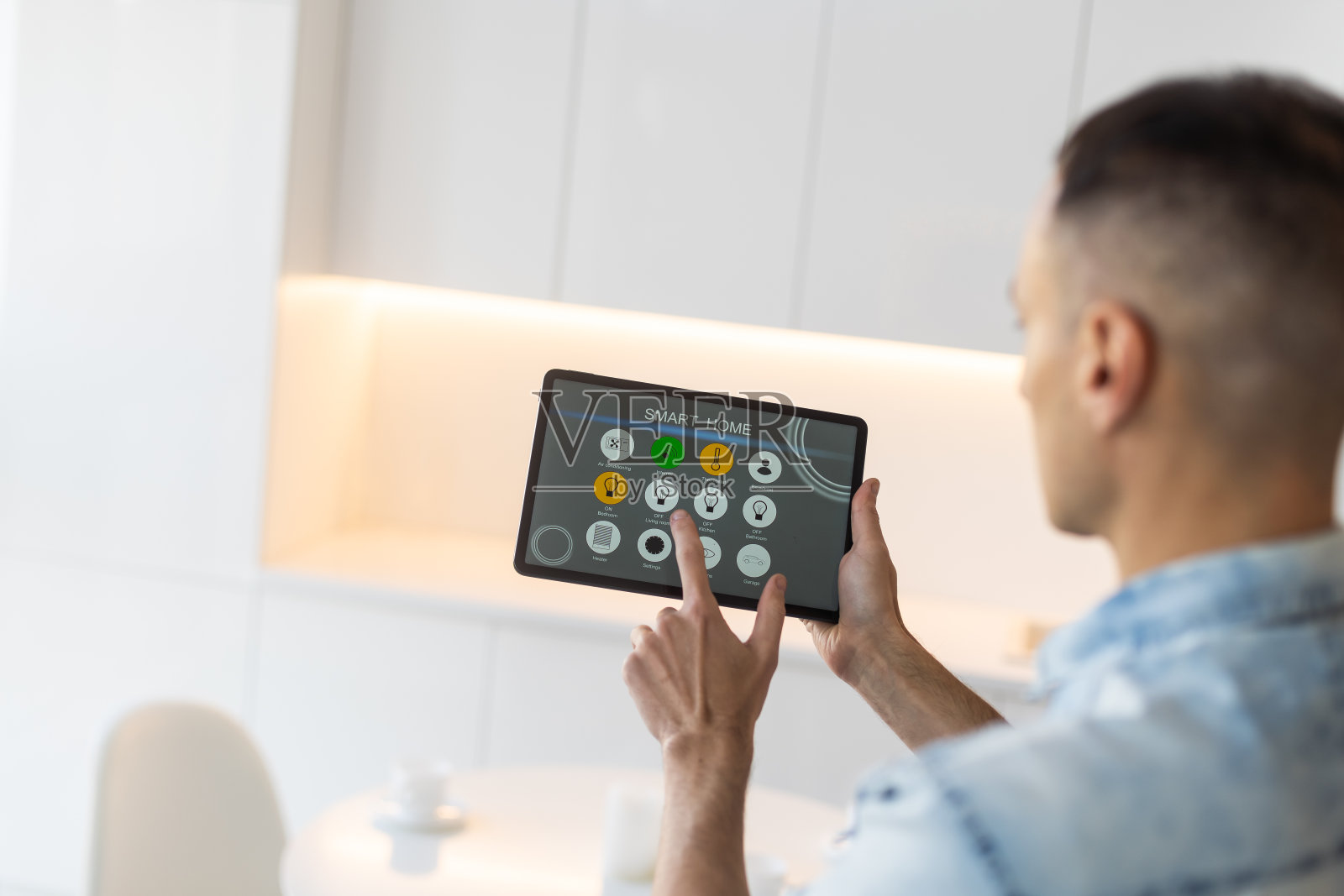 男子手持平板电脑，屏幕上显示智能家居应用程序照片摄影图片